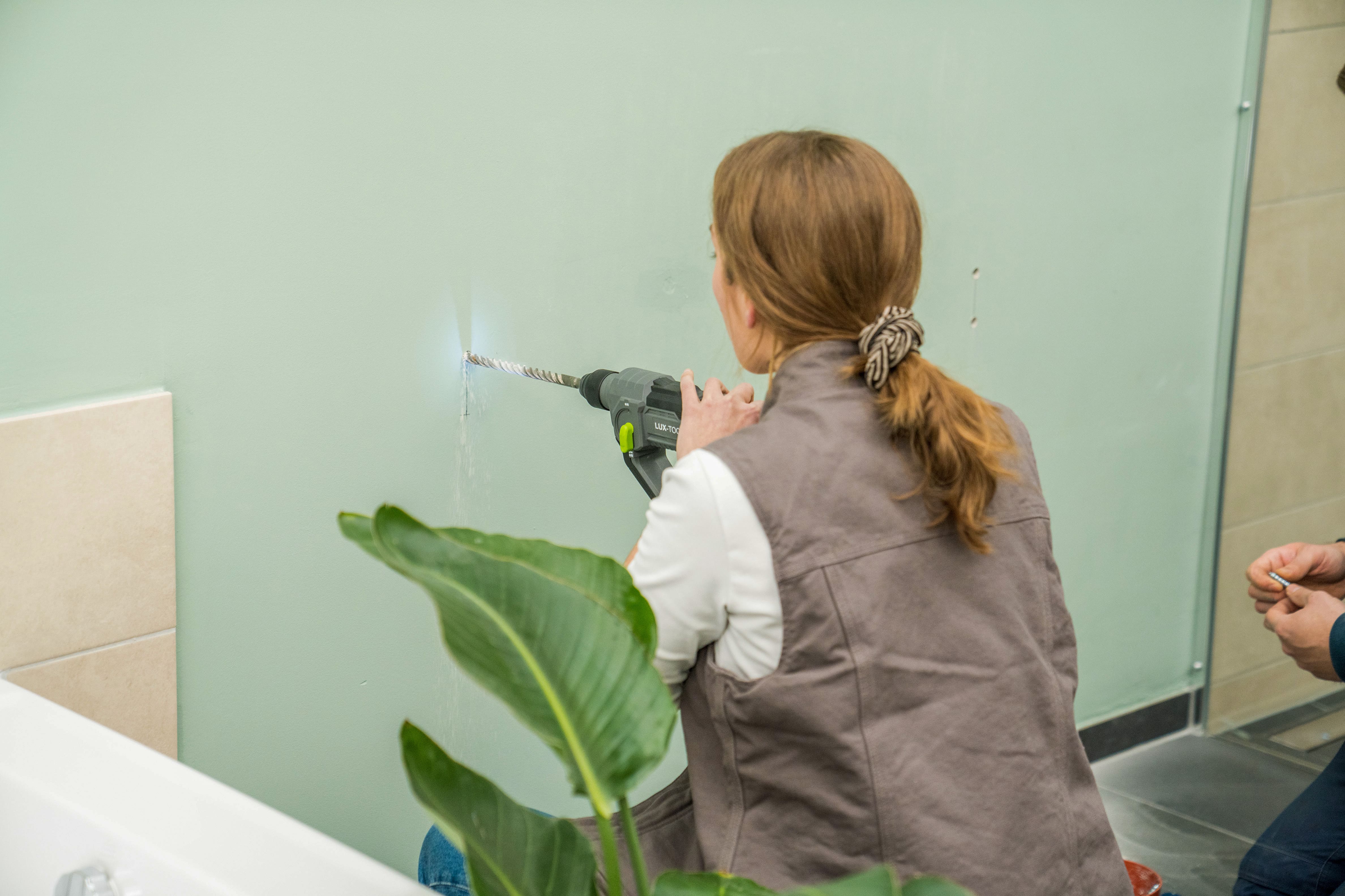 Jemand bohrt ein Loch in eine massive Wand.