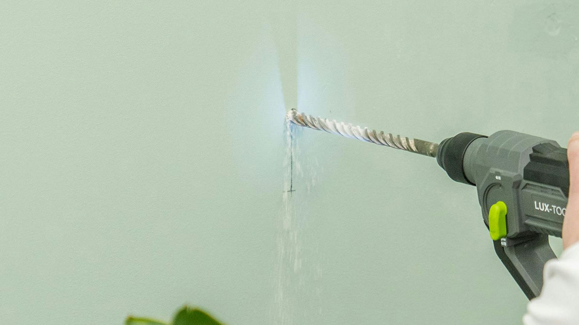 Jemand bohrt ein Loch in eine massive Wand.