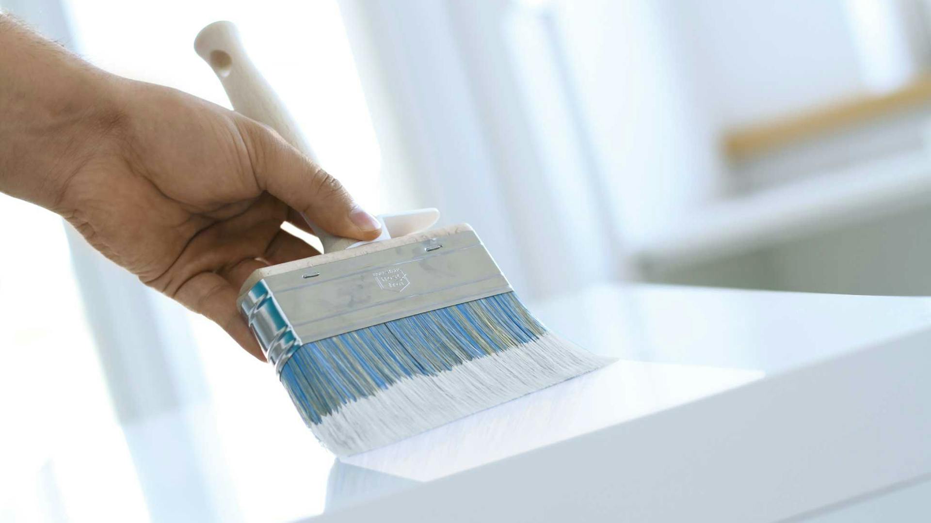 Il piano del tavolo bianco viene verniciato con una pennellessa.