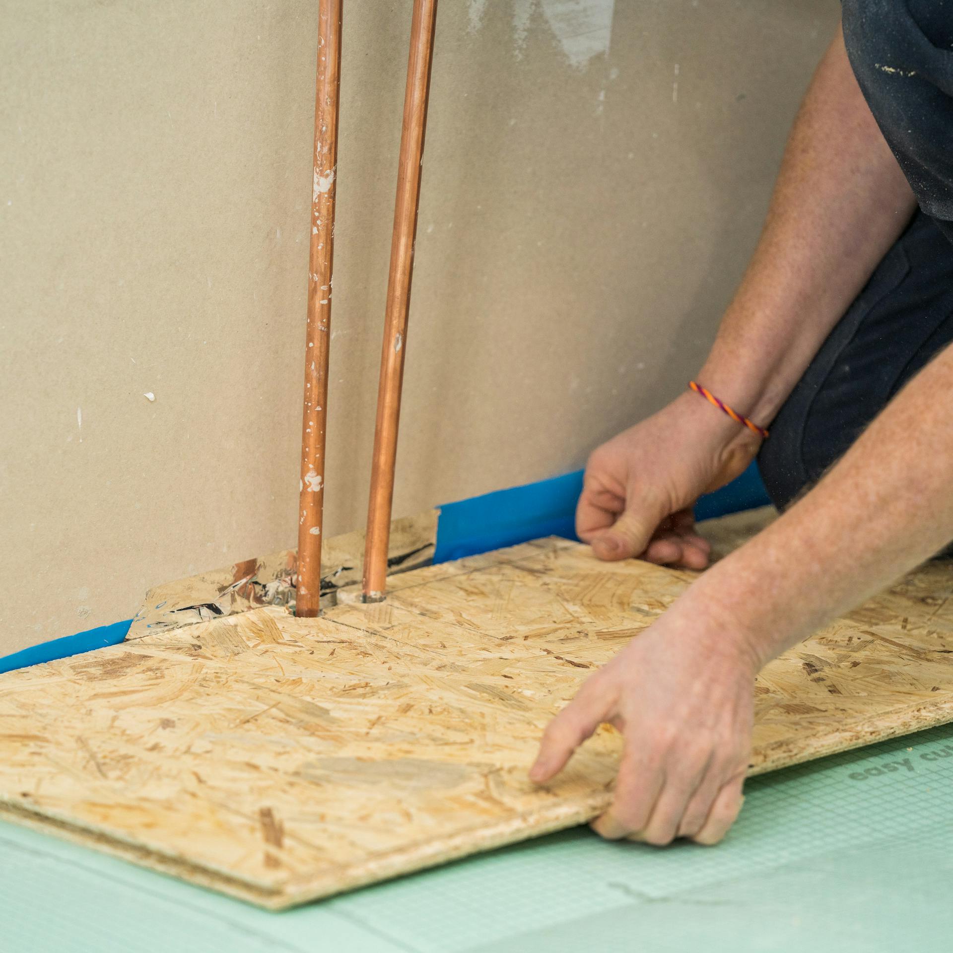 Heimwerker legt die zugeschnittene Platte wieder an die Wand.