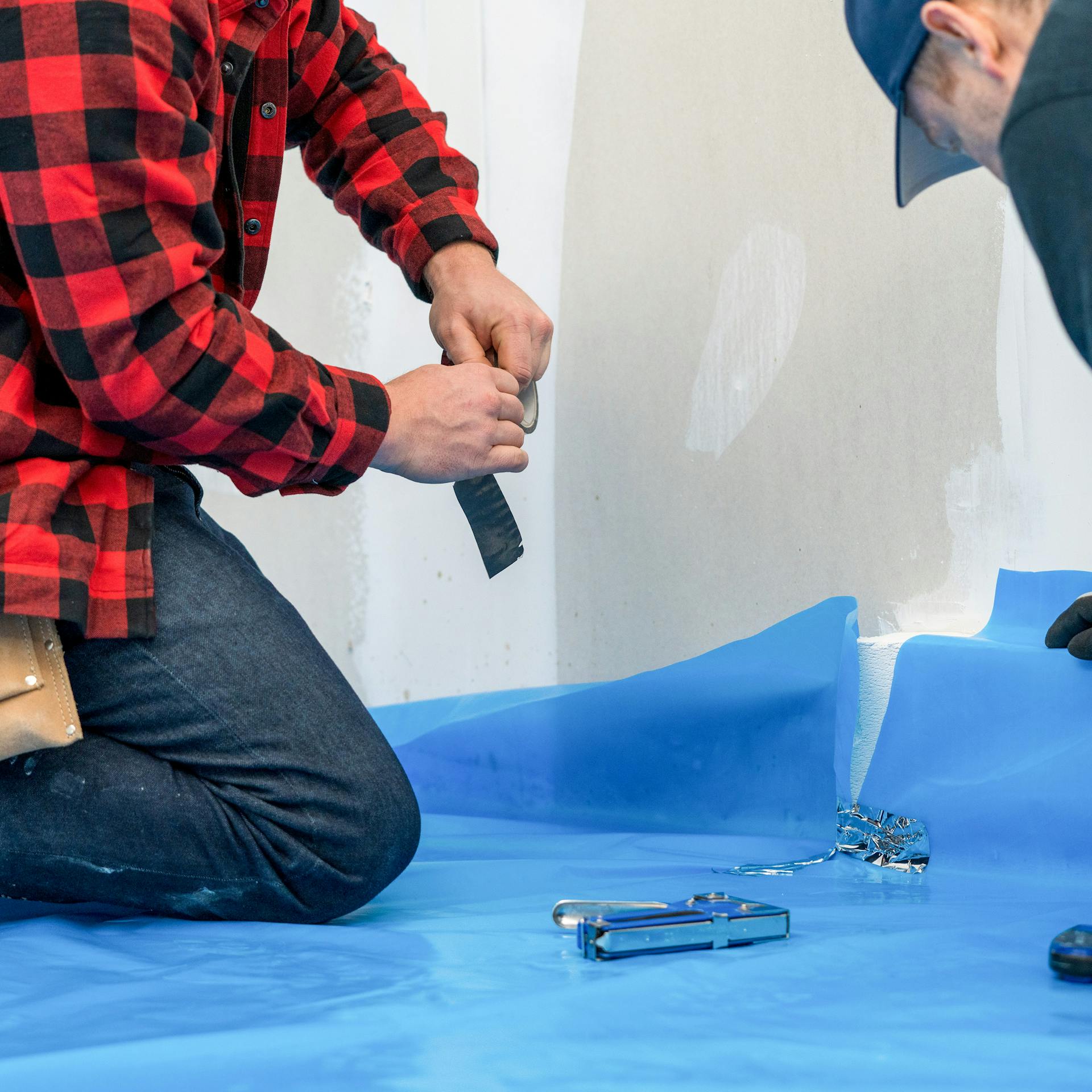 Heimwerker verlegt die Dampfbremse auf den Boden.