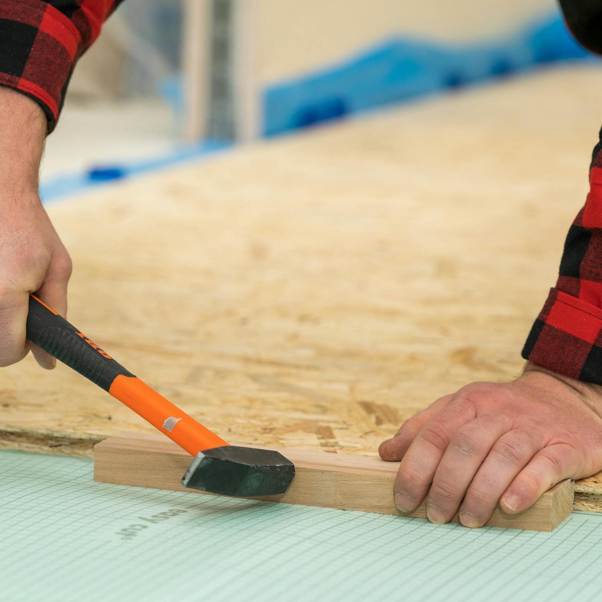 Heimwerker richtet OSB-Platten präzise mit Hammer und Schlagholz aus.