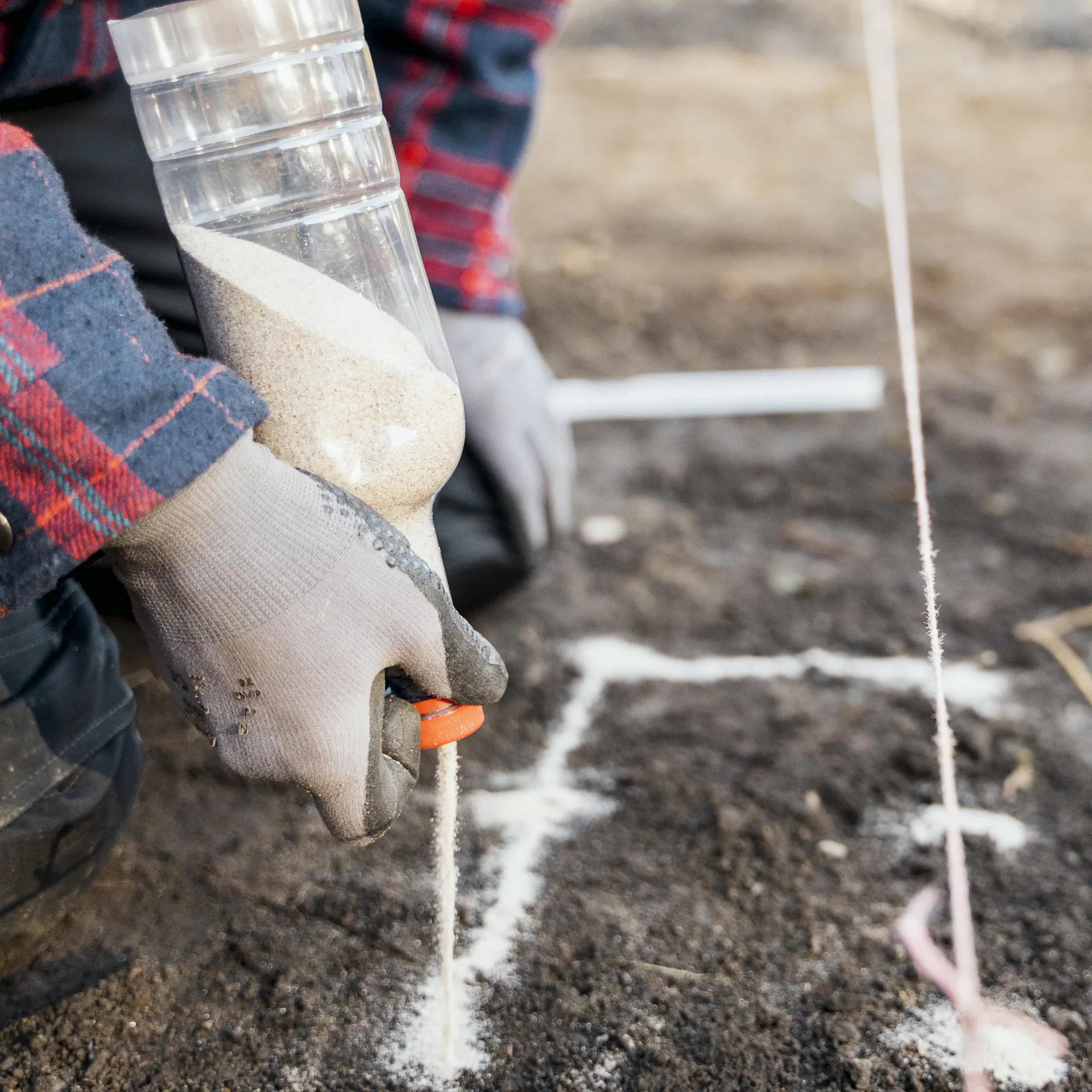 Heimwerker markiert die Stellen für das Punktfundament mit Sand.