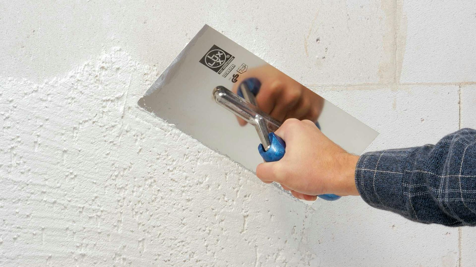 Heimwerker glättet frisch aufgetragenen Putz mit einer Glättekelle.