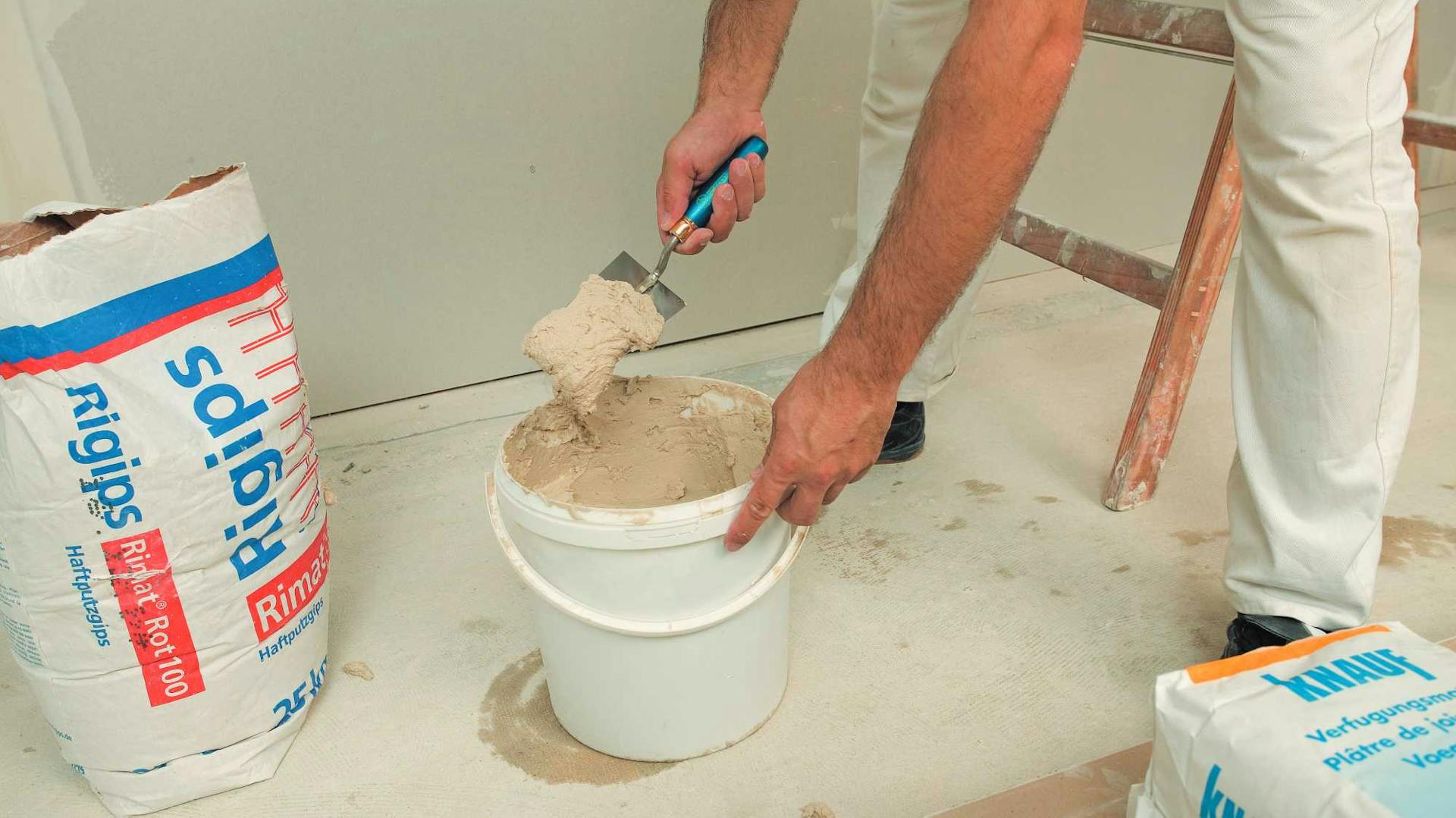 Heimwerker rührt im Eimer Putz an.