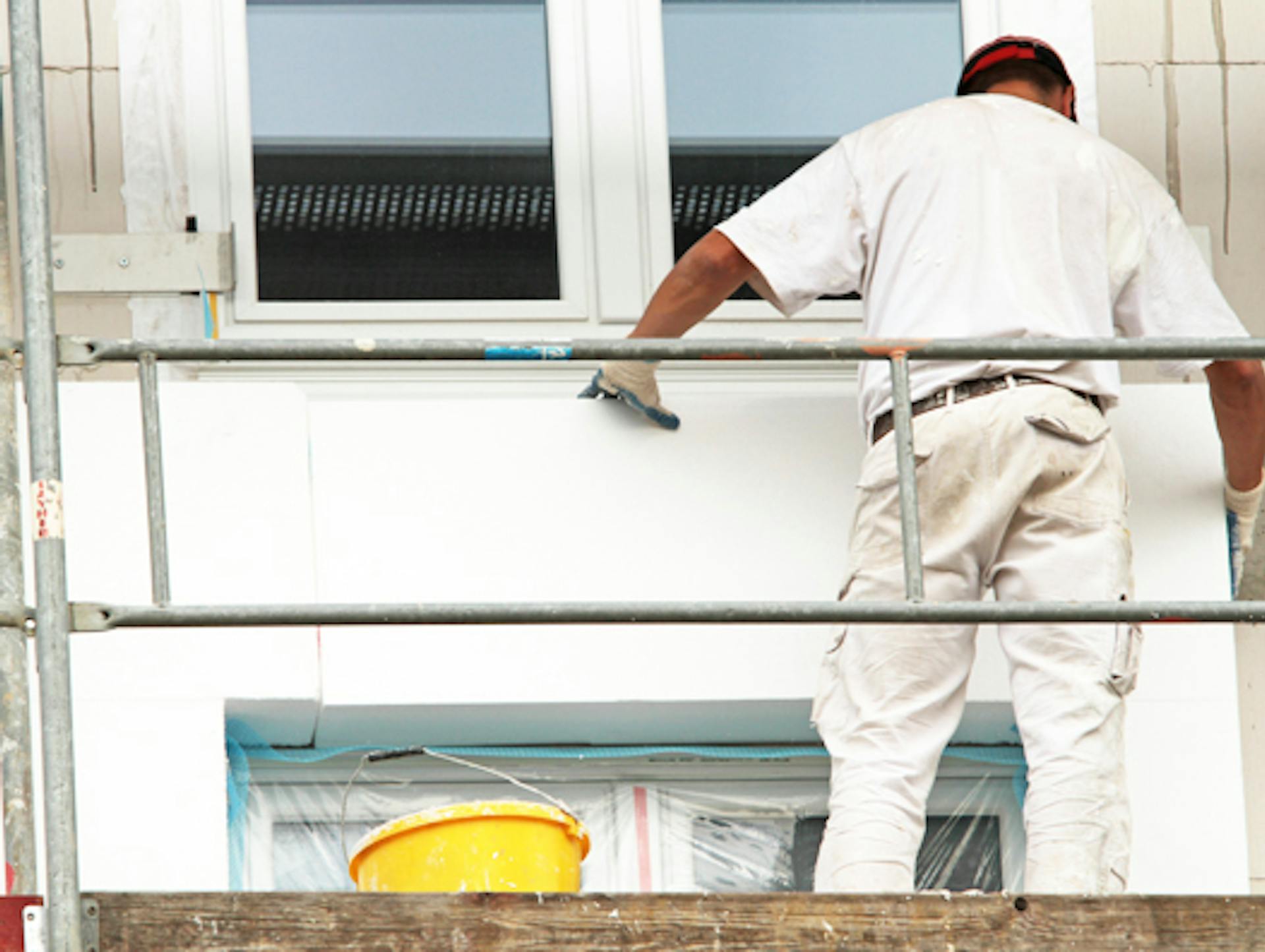 Ein Mann dämmt die Fassade eines Neubaus.