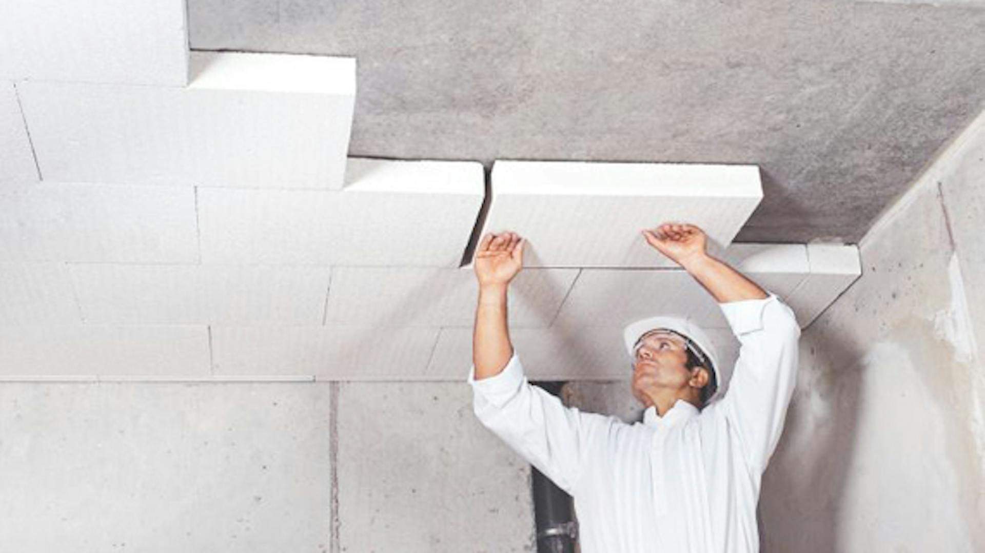 Az ezermester szigetelőanyagot rögzít az alagsor mennyezetére.