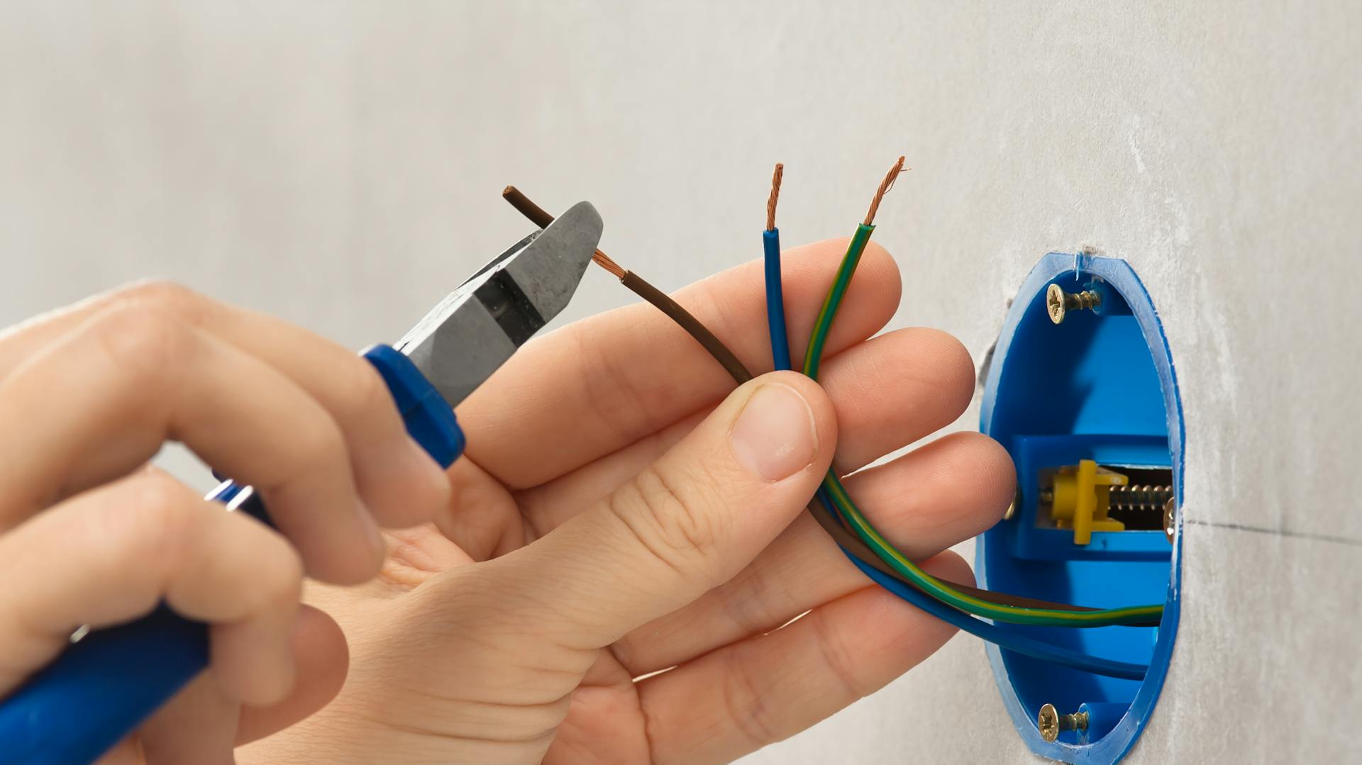 Jemand verdrahtet Stromkabel in einer Wandanschlussdose