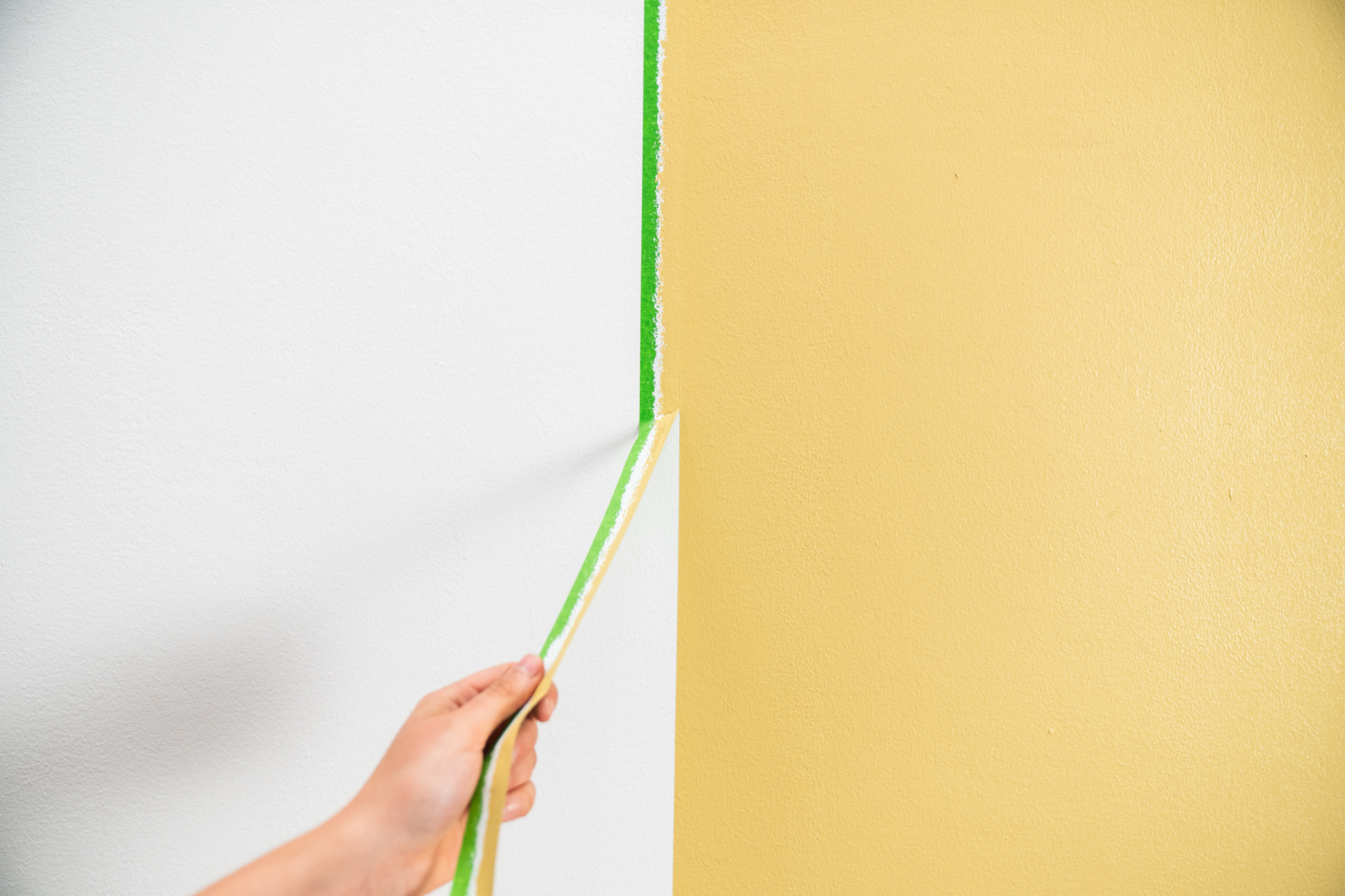 Osoba sťahuje zo steny maliarsku pásku