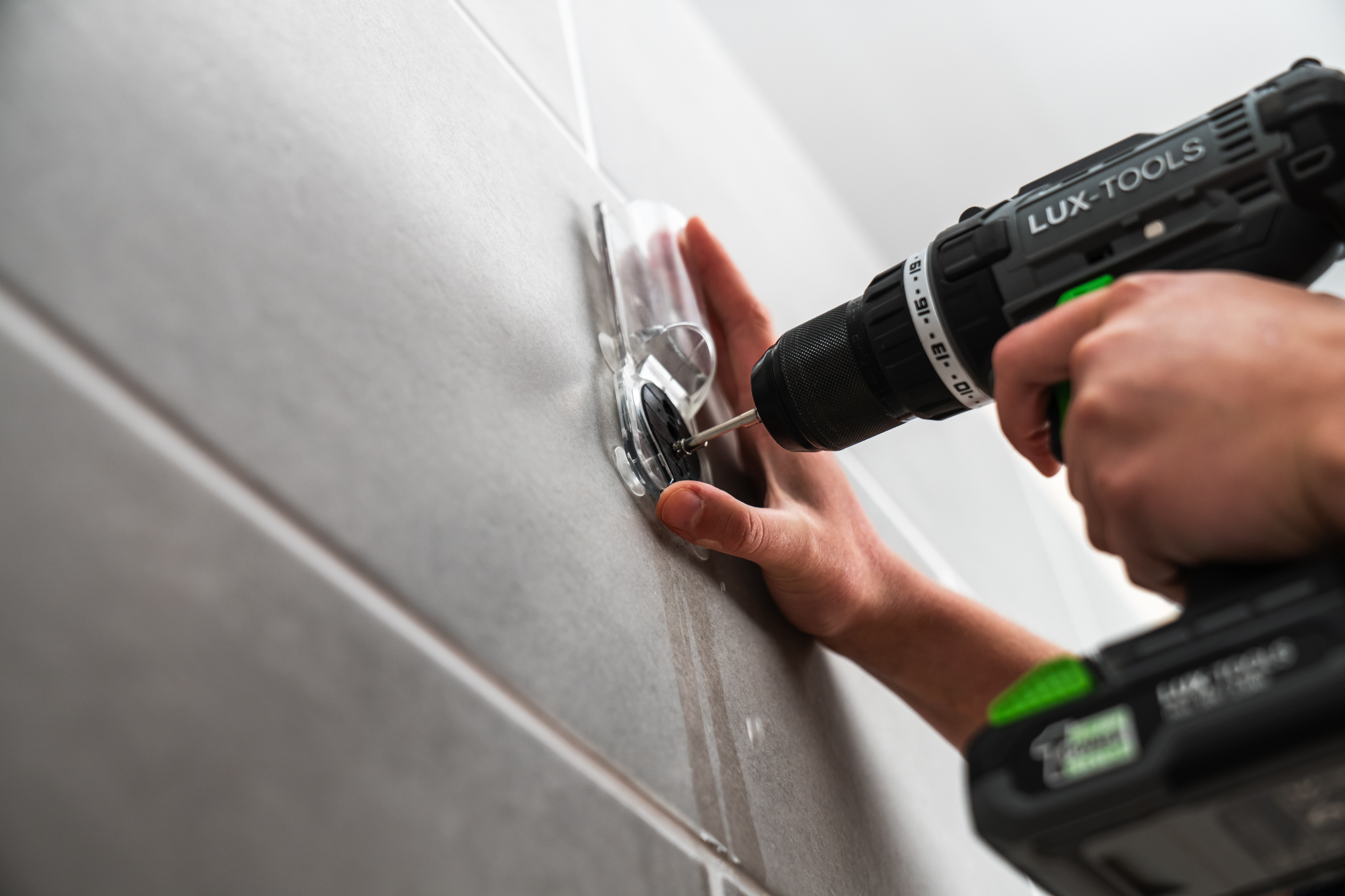 Osoba skrutkuje do dlažby pomocou vedenia