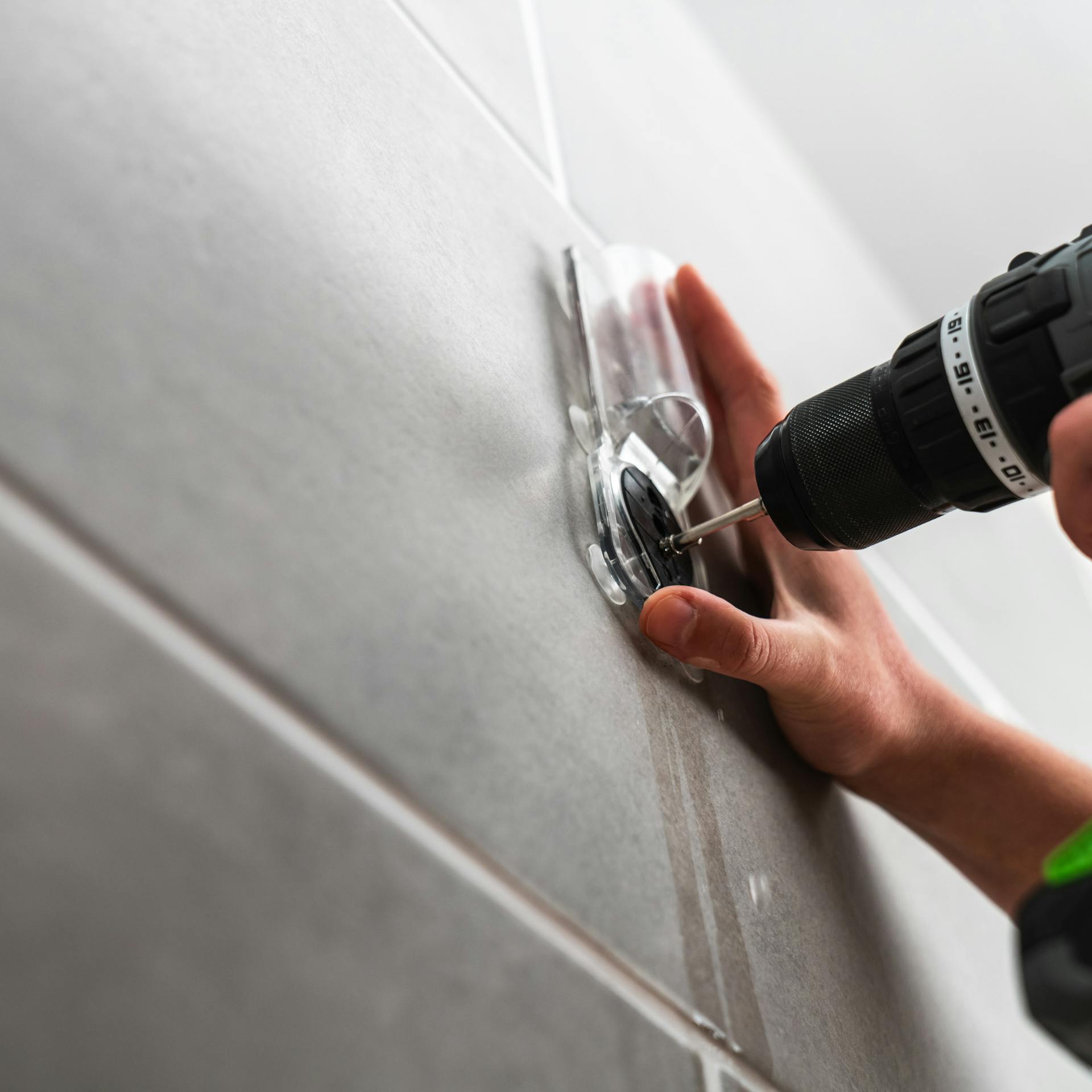 Osoba skrutkuje do dlažby pomocou vedenia