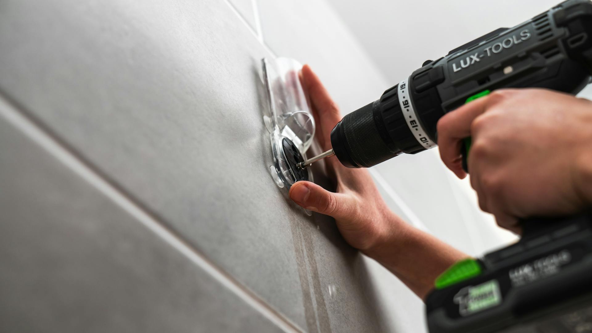 Eine Person bohrt mit einem Bohrer in Fliesen.