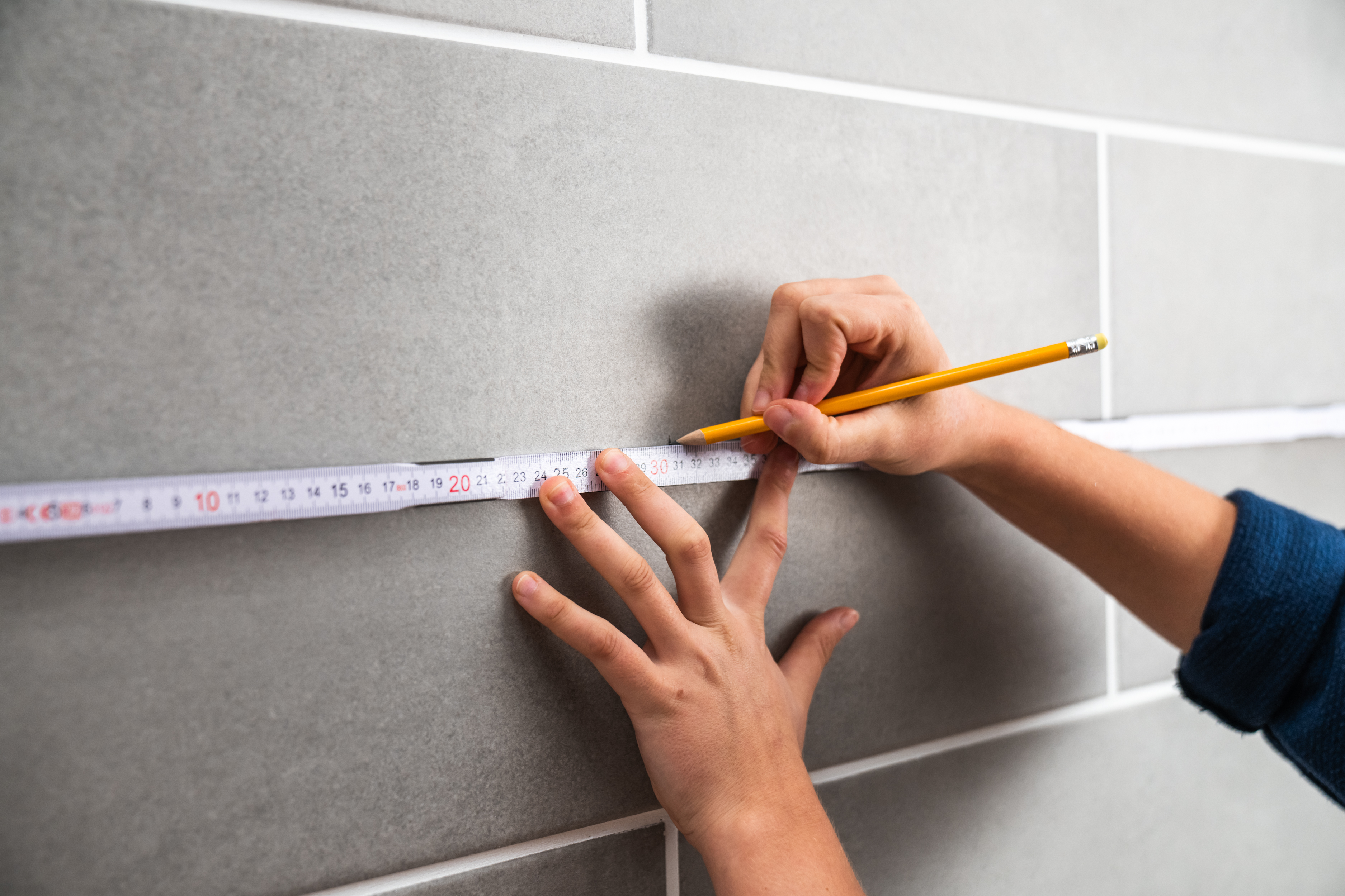 Osoba si ceruzkou označuje obkladačku