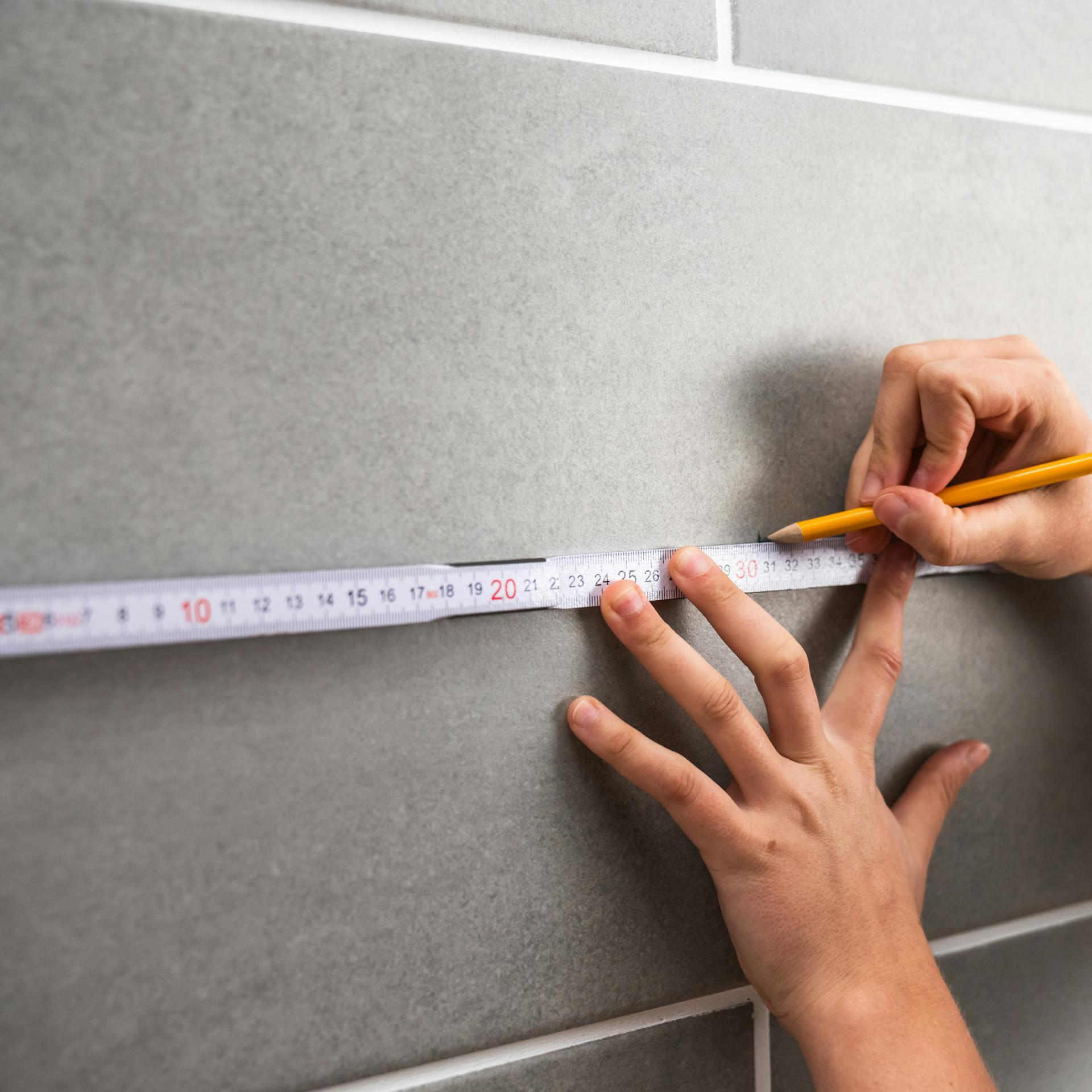 Person markiert mit einem Bleistift auf der Fliese.