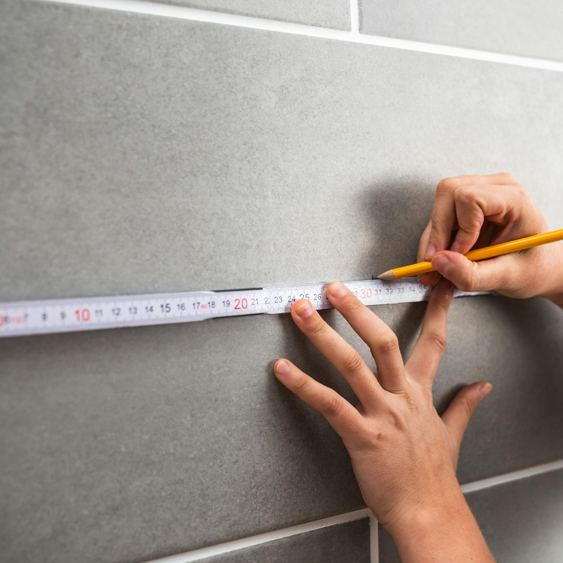 Osoba si ceruzkou označuje obkladačku