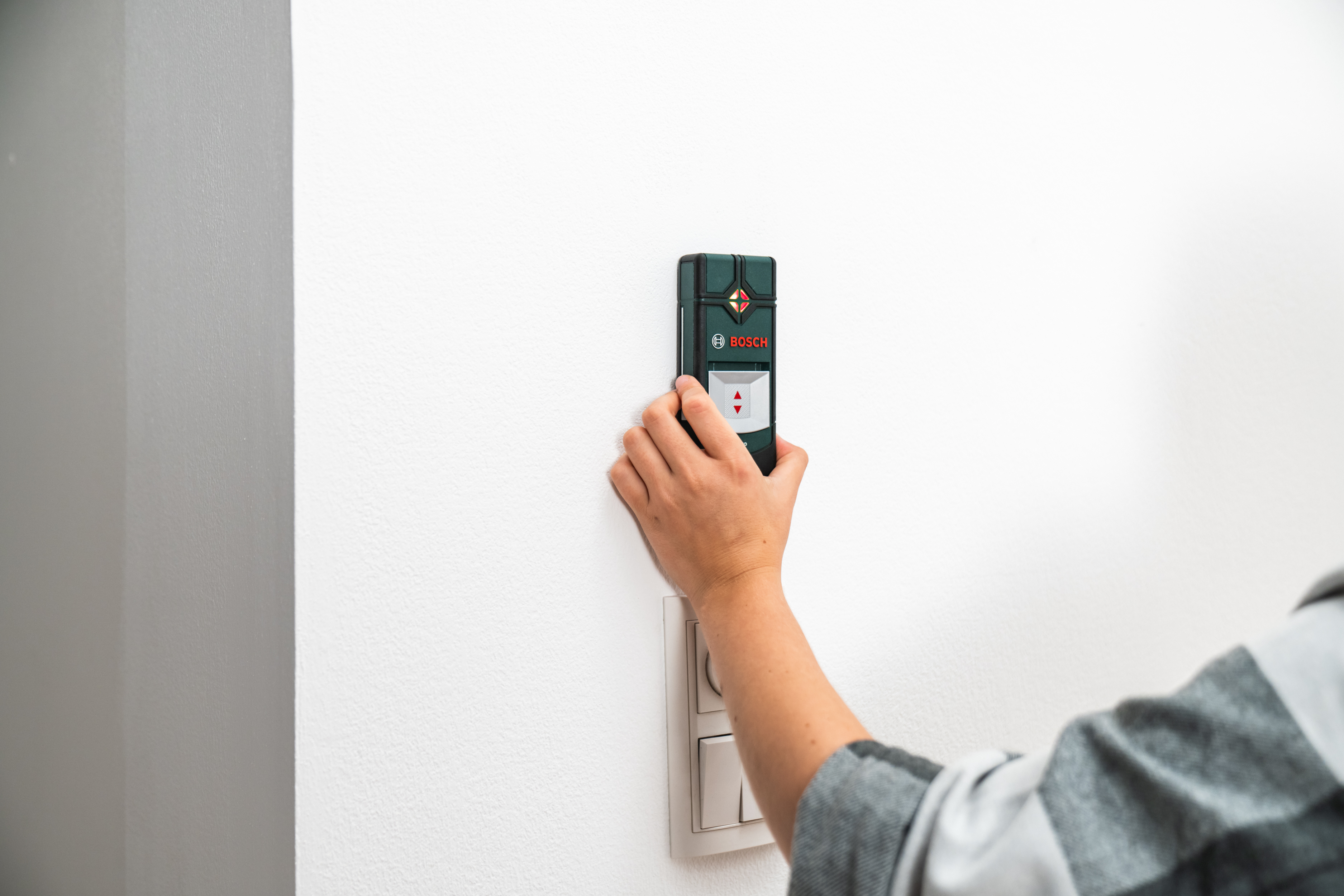 Osoba pridržiava detektor vedení na stene