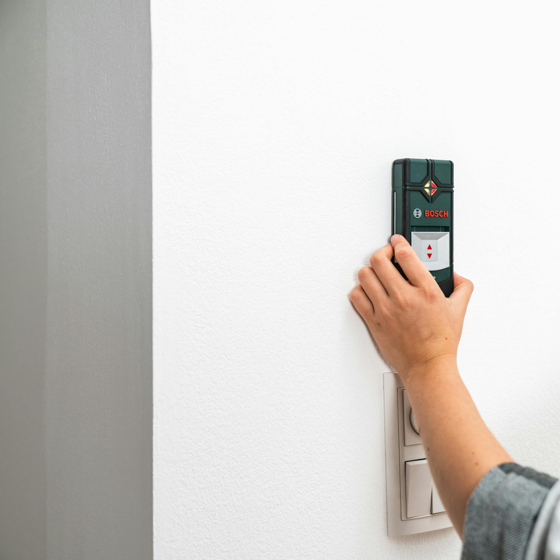 Osoba pridržiava detektor vedení na stene