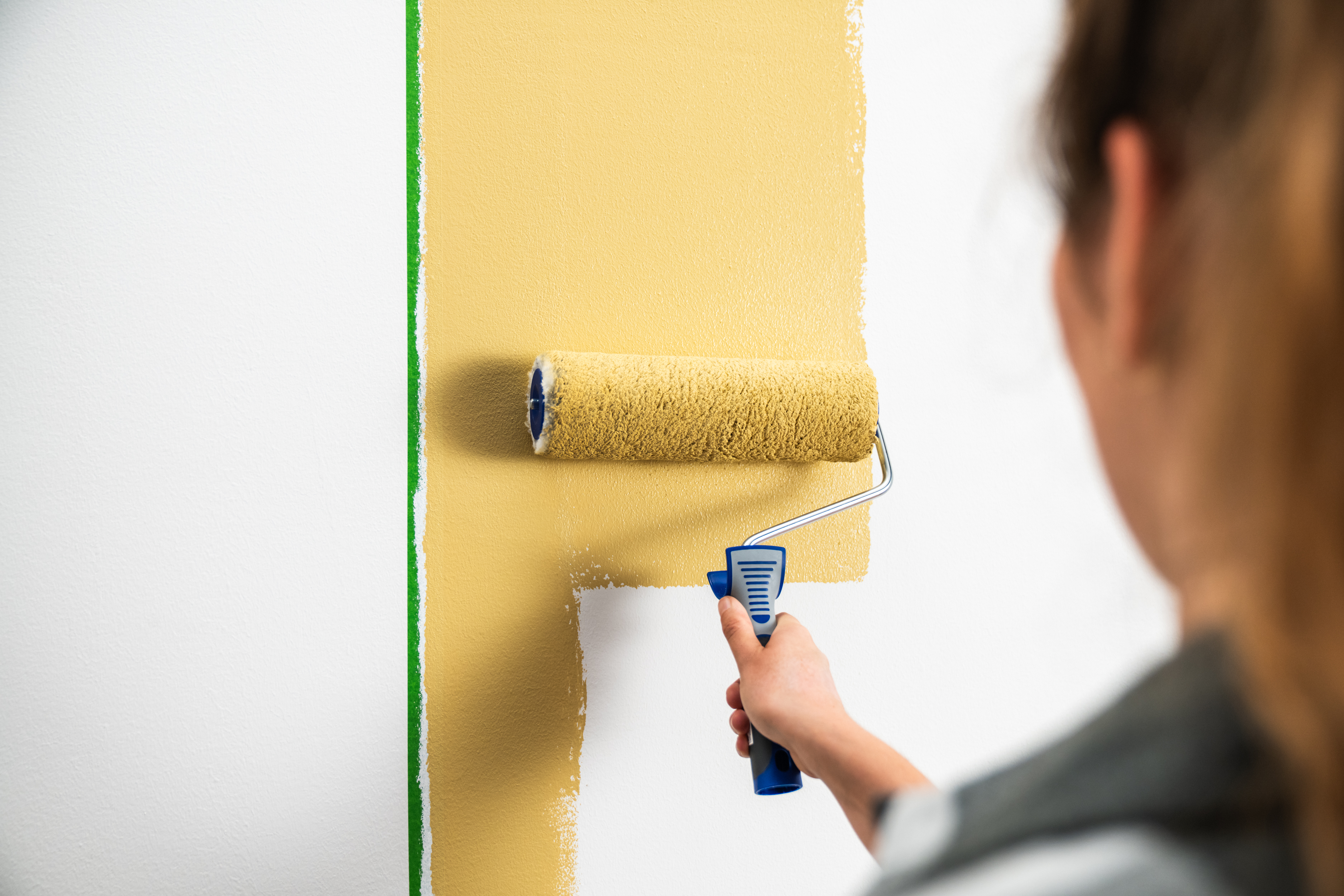 Pracovníčka natiera stenu maliarskym valčekom