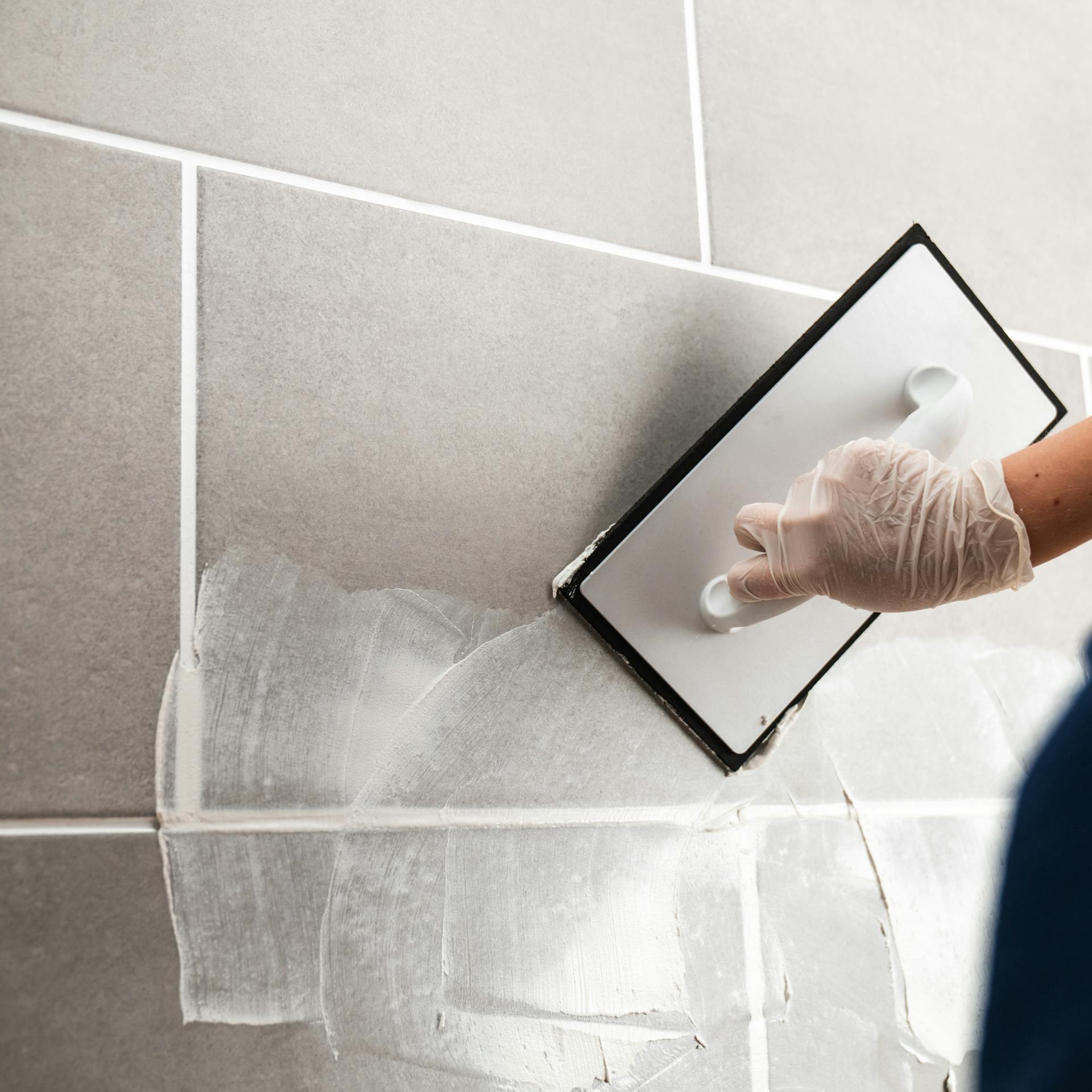 Person spachtelt Fliesen.