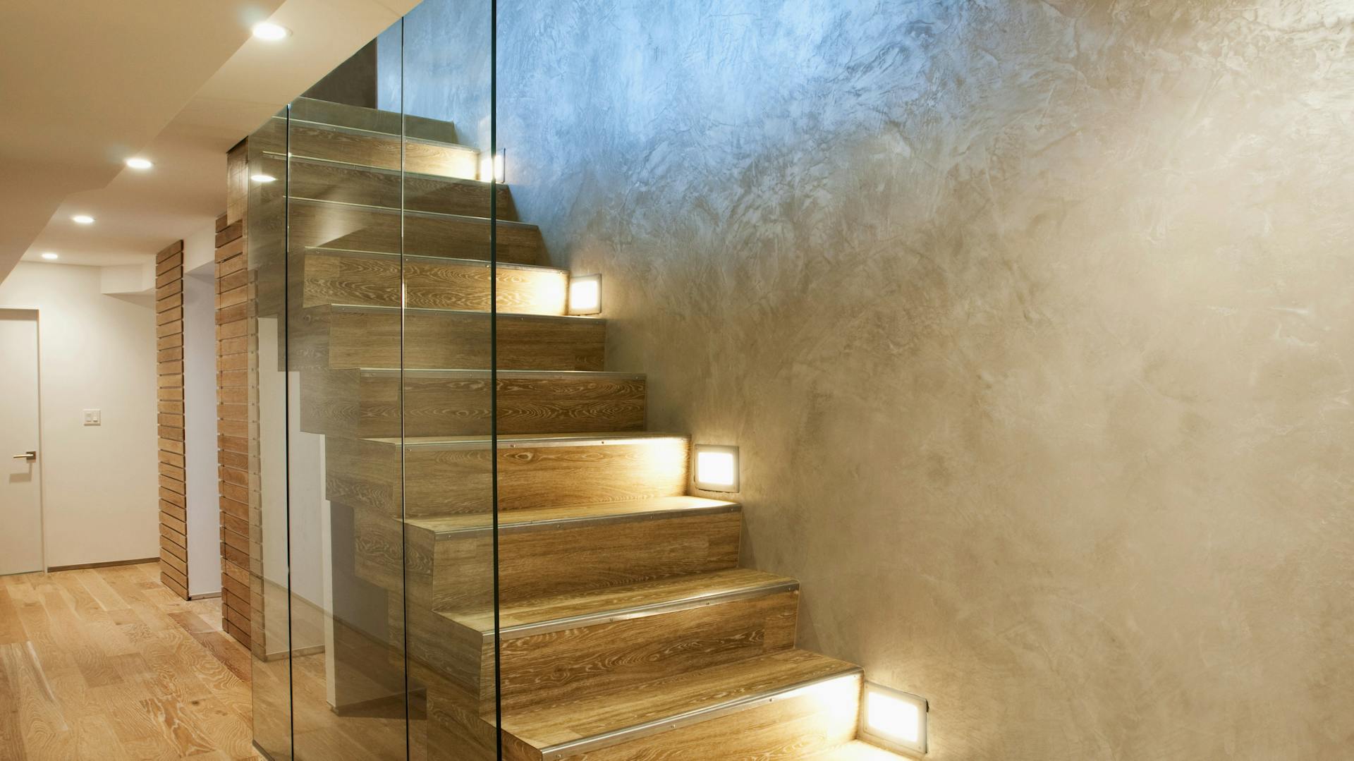 Holztreppe im Haus mit Glaswand und Einbaustrahlern an Wand