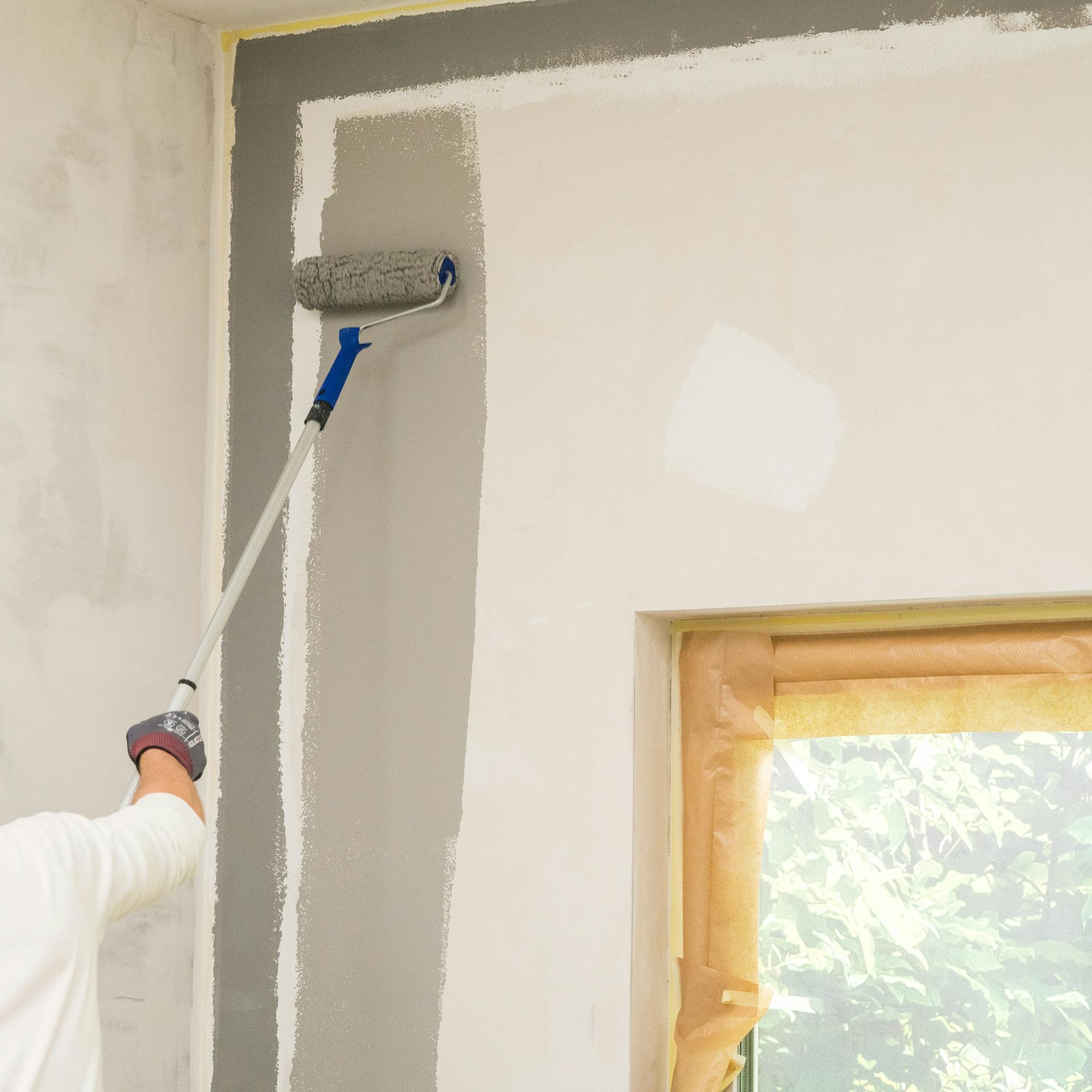 Heimwerker bringt den ersten Anstrich auf.