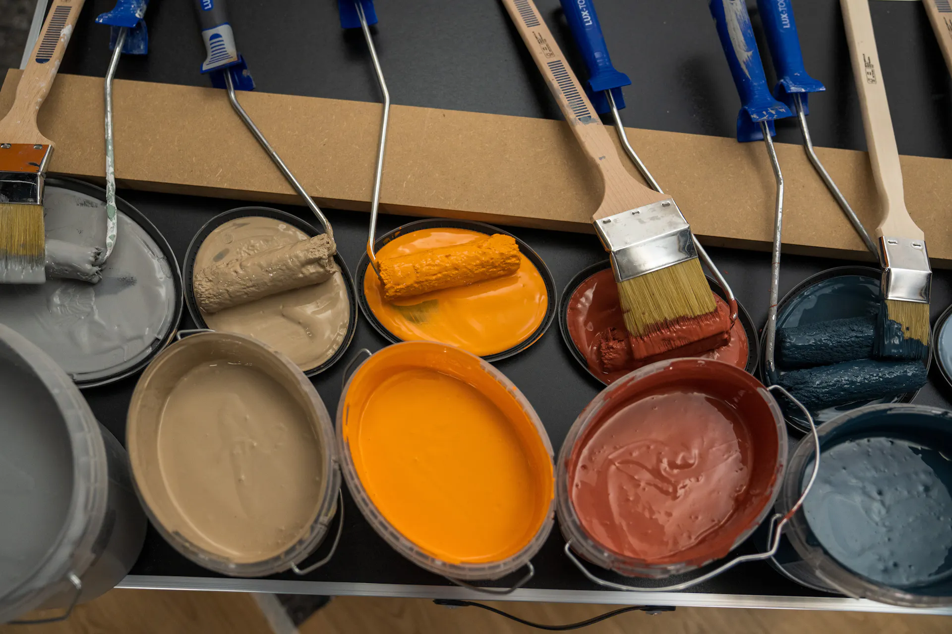 De nombreux pots de peinture avec différentes couleurs, rouleaux et pinceaux.