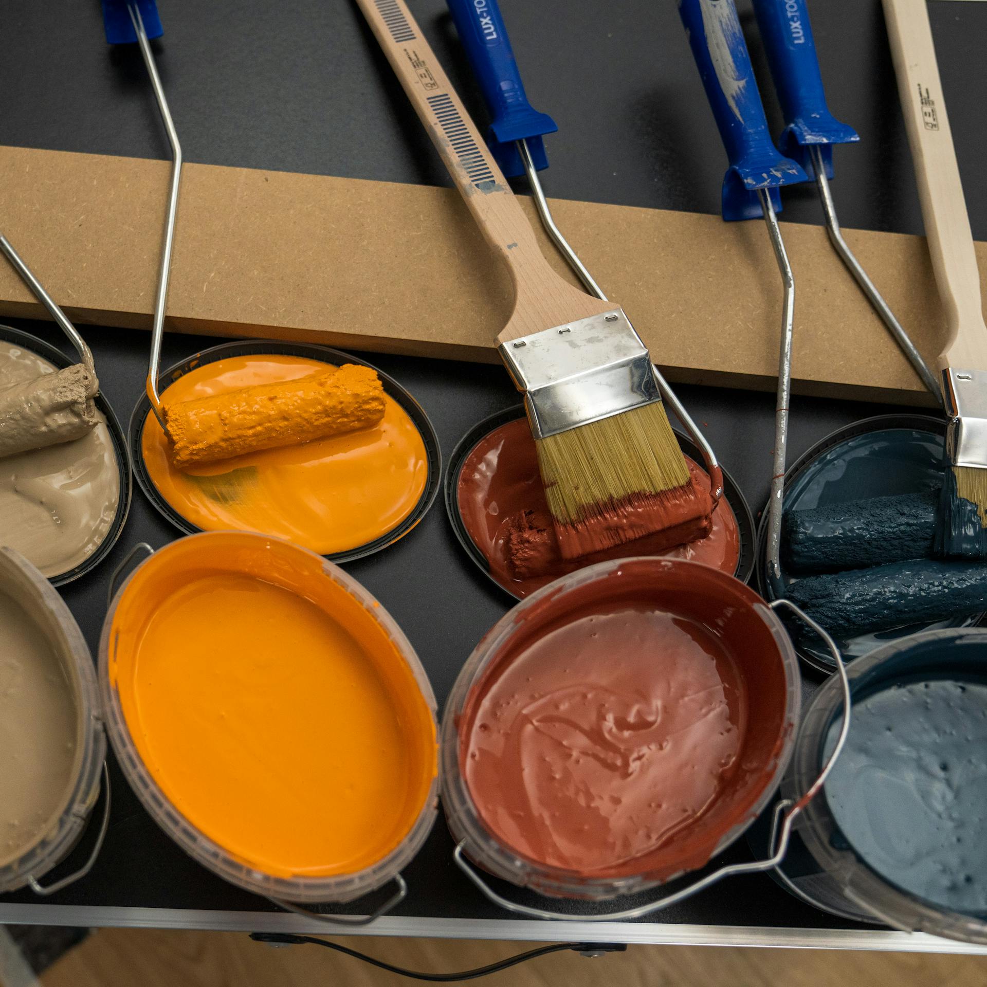 Viele Farbtöpfe mit unterschiedlichen Farben, Rollen und Pinseln.