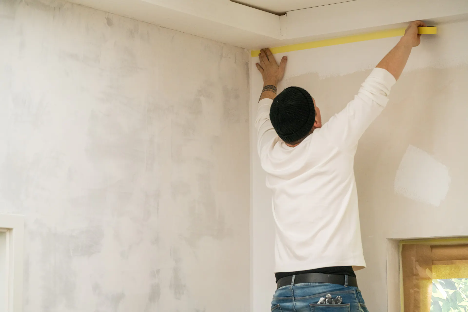 Un artisan peint la frise avant de peindre les murs.