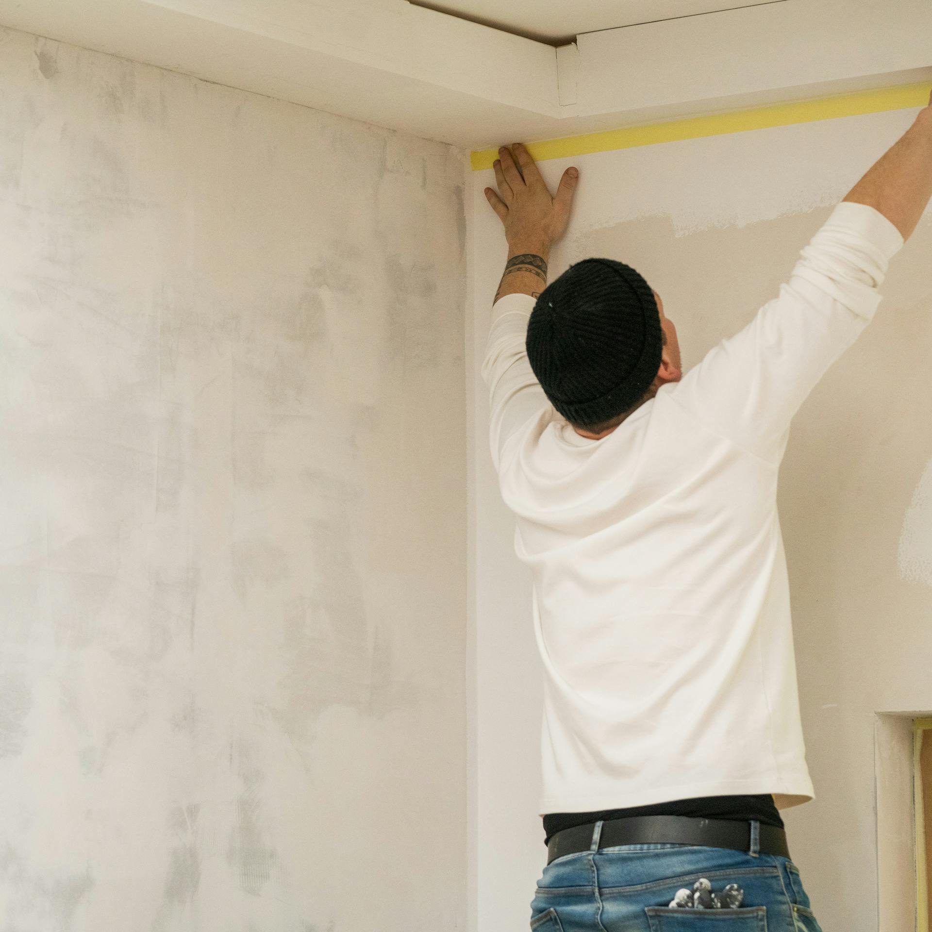 Handwerker streicht den Fries vor dem Streichen der Wände.