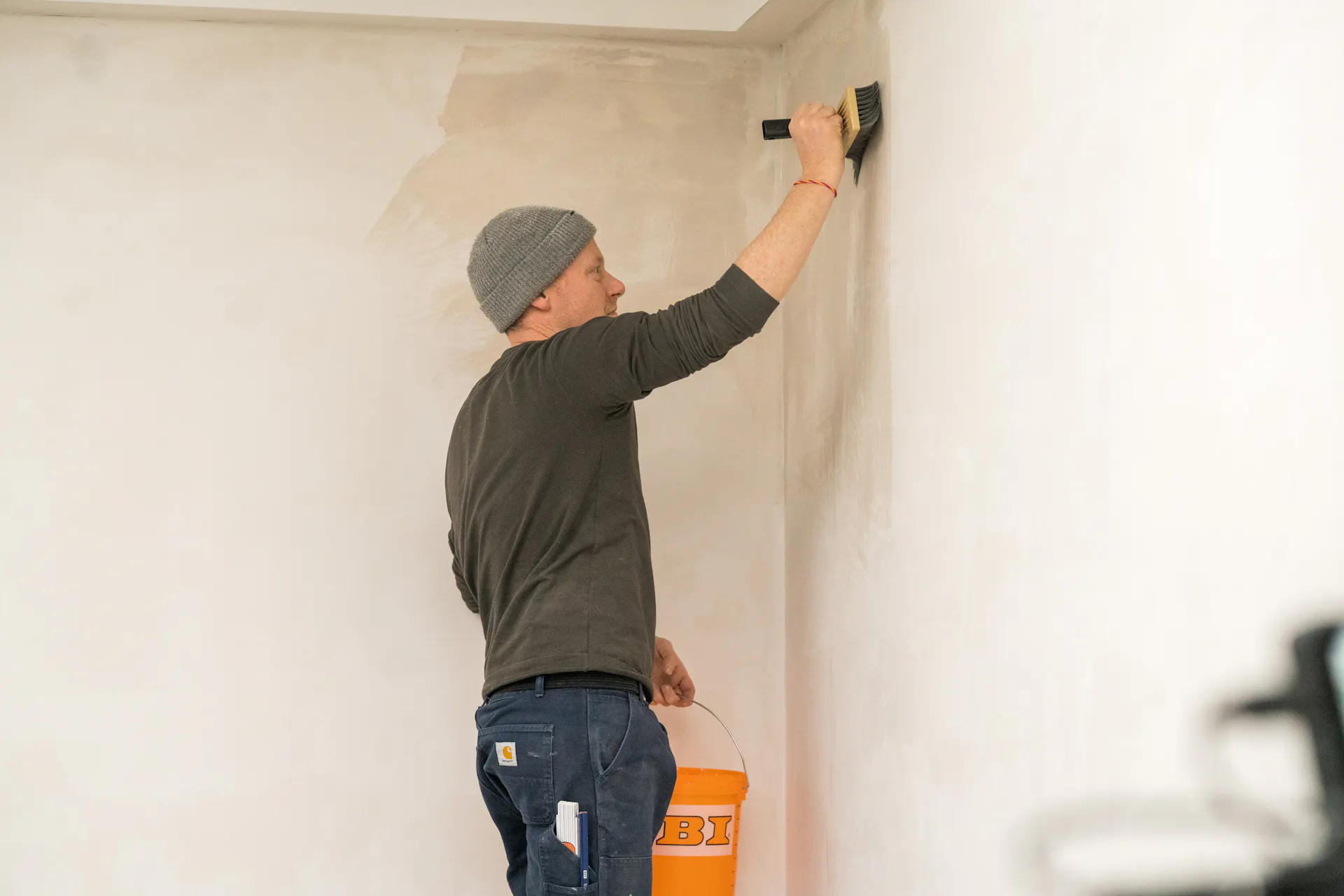 Un bricoleur apprête le mur avant de le peindre.