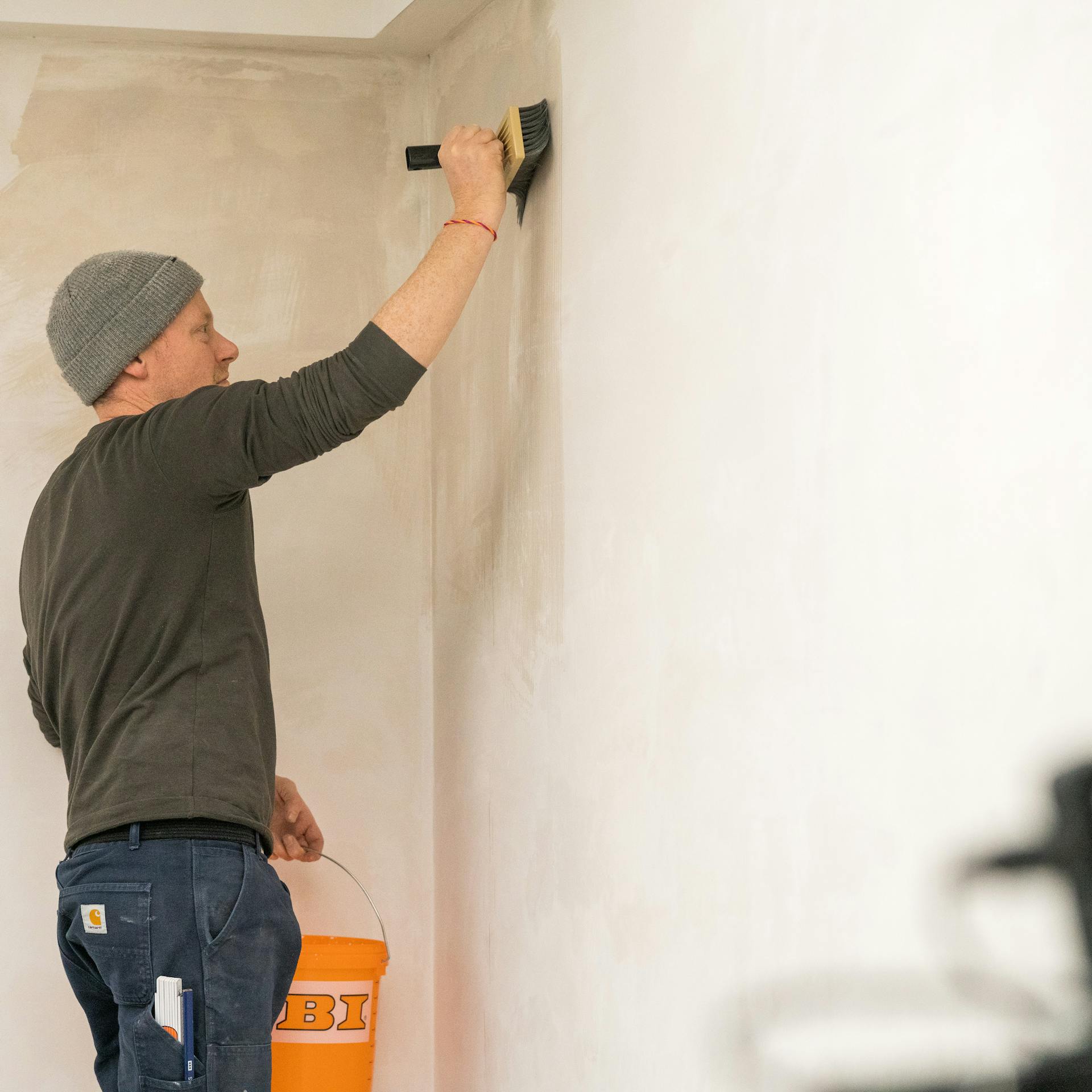 Heimwerker grundiert Wand vor dem Streichen.