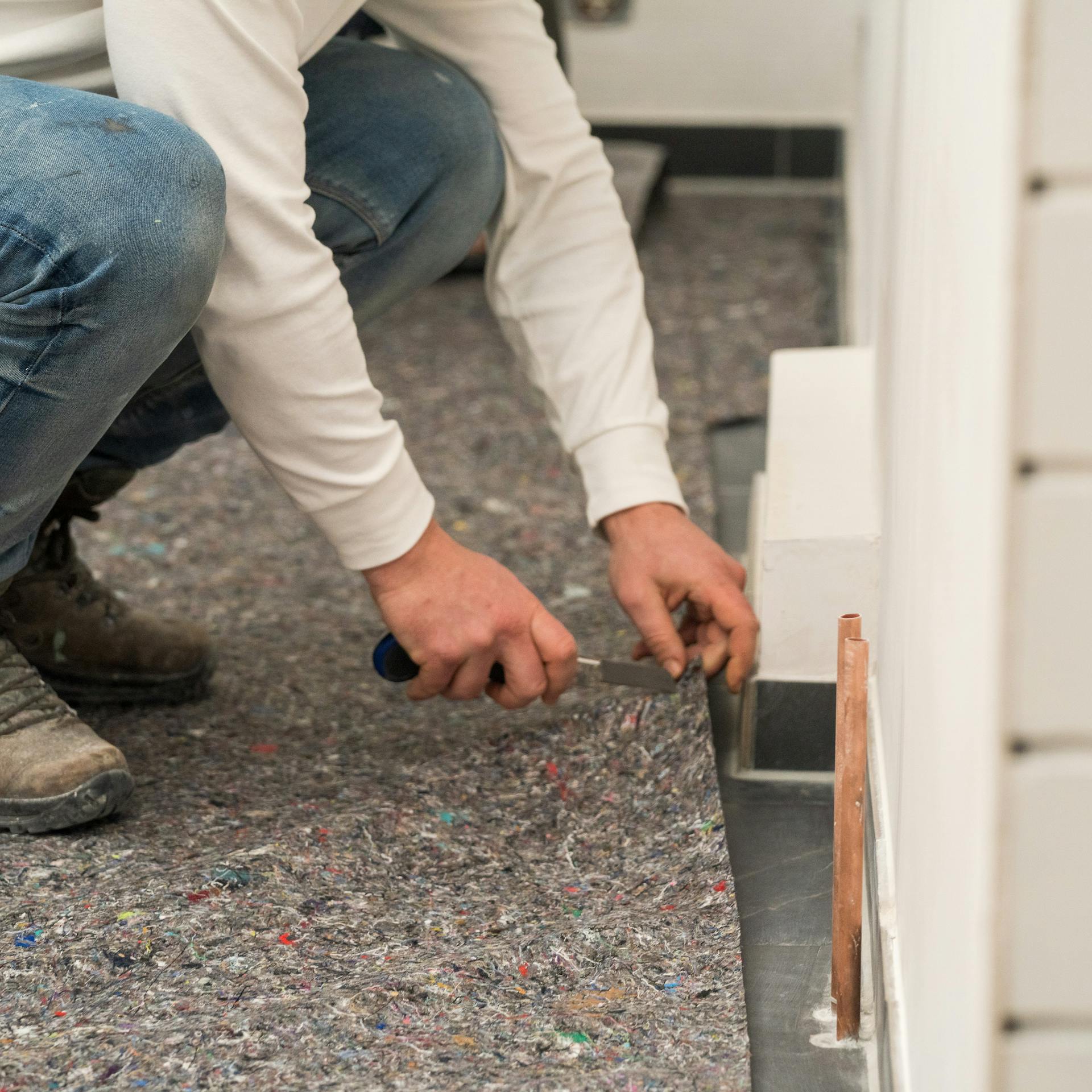 Heimwerker legt Malerkrepp auf den Boden.