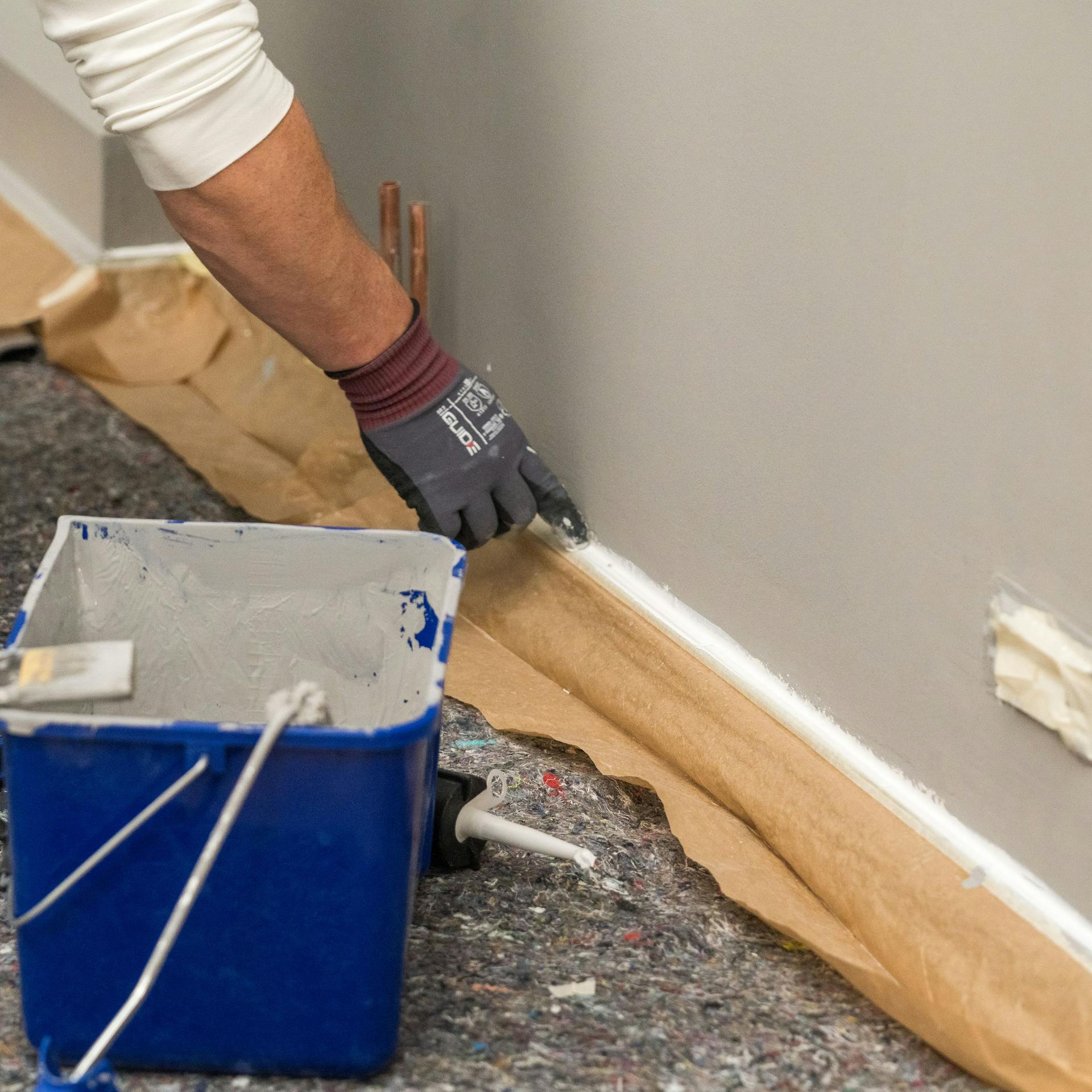 Heimwerker trägt Acryl auf den Übergang der Wände auf.