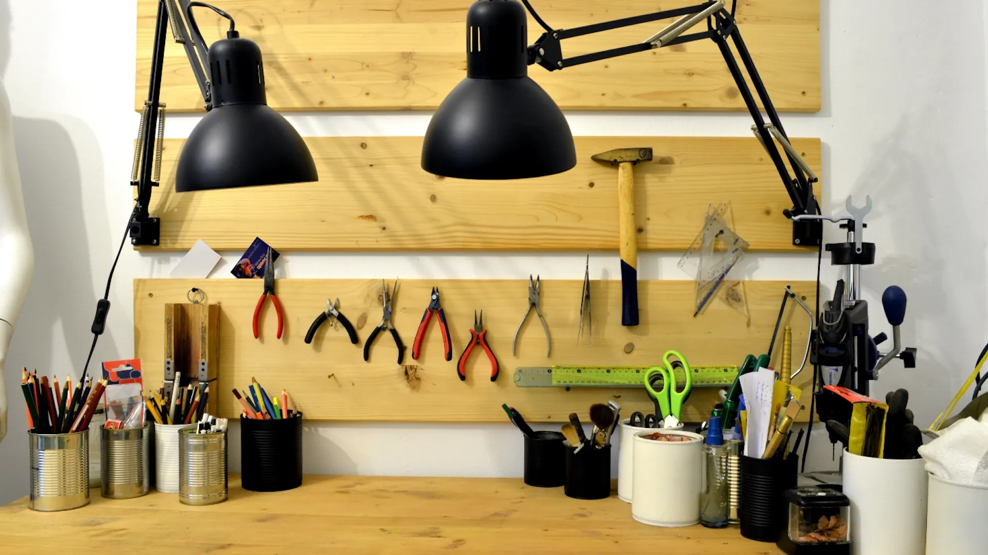 Piccolo banco da lavoro con utensili e due lampade a destra e sinistra.