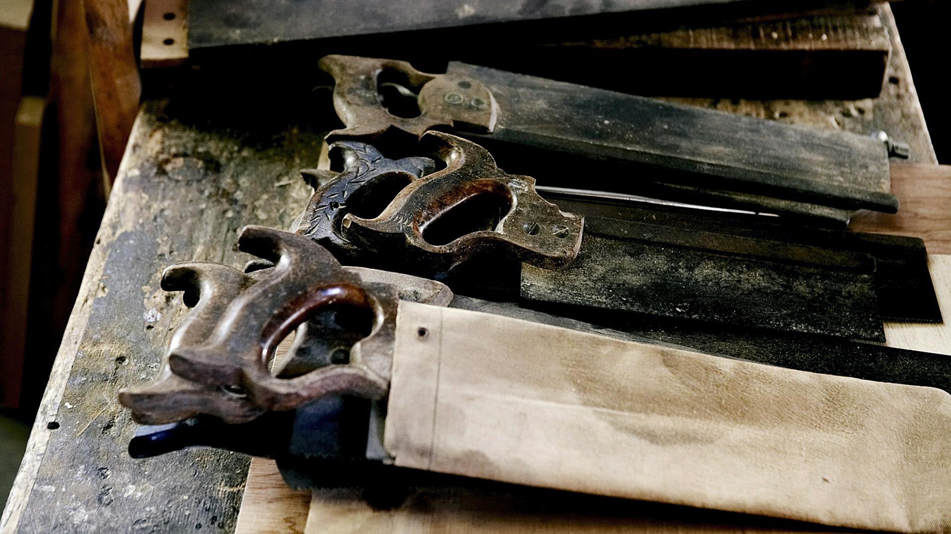 Verschiedene Sägen liegen auf einer Werkbank aus Holz.