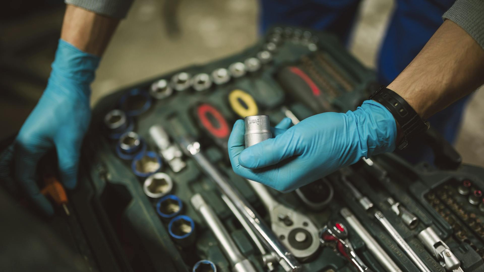 Jemand nimmt eine 19er-Nuss aus dem Werkzeugkoffer.