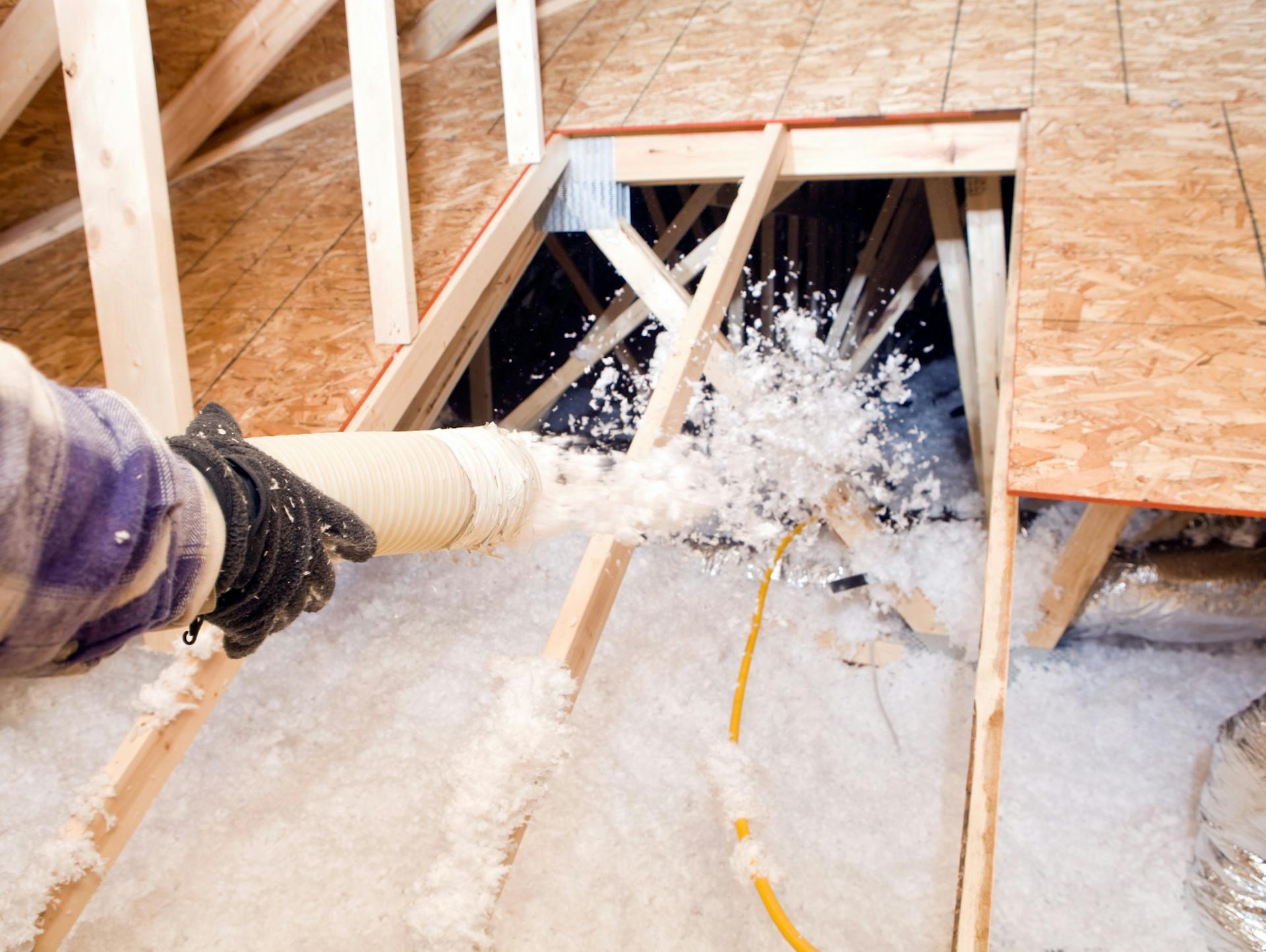Valaki befújható szigetelést visz fel a tetőtérbe.