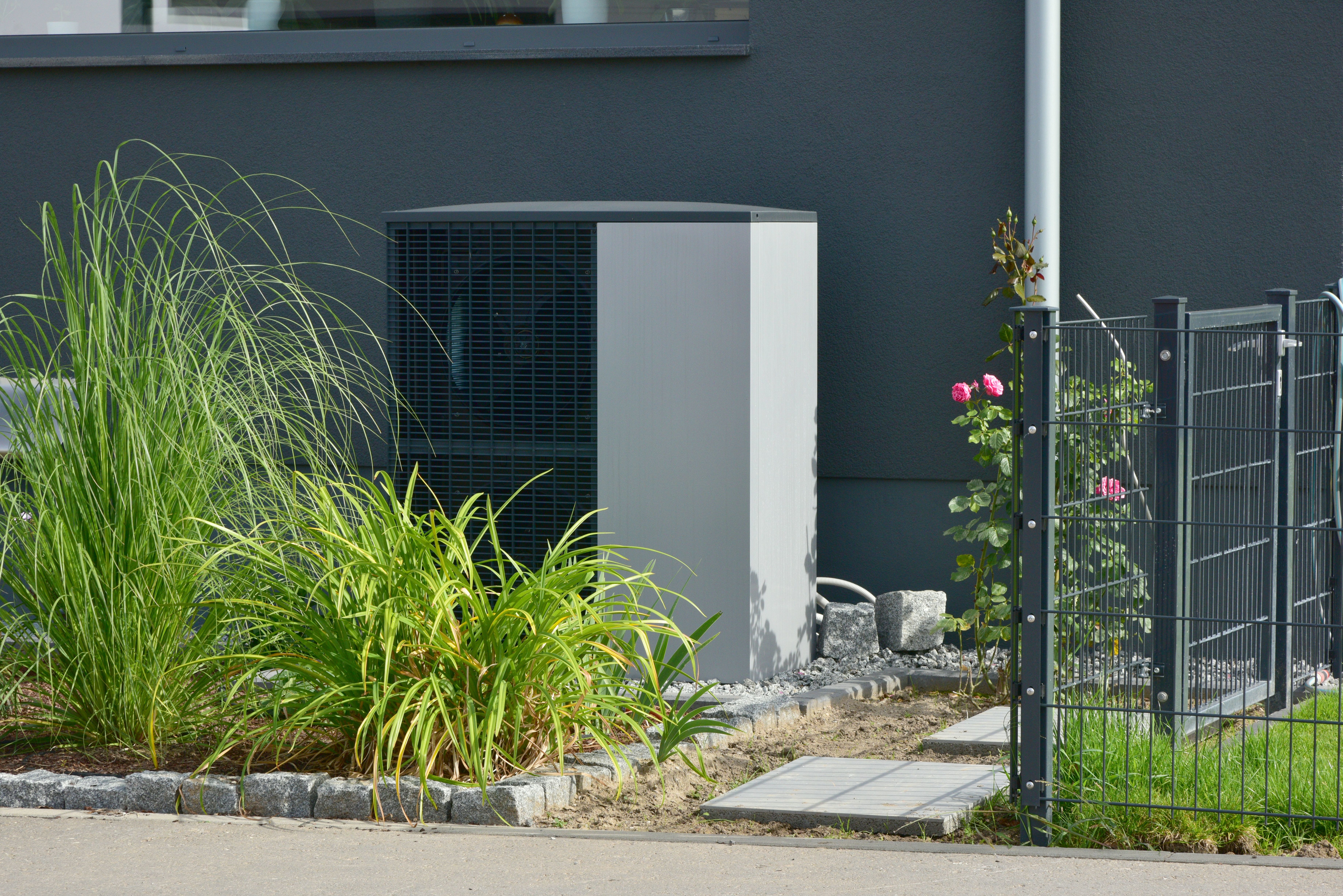 Luft-Luft-Wärmepumpe für Heiz- und Warmwasser vor einem neuen Wohngebäude