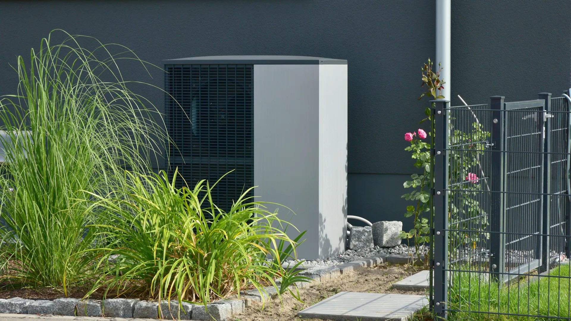 Luft-Luft-Wärmepumpe für Heiz- und Warmwasser vor einem neuen Wohngebäude