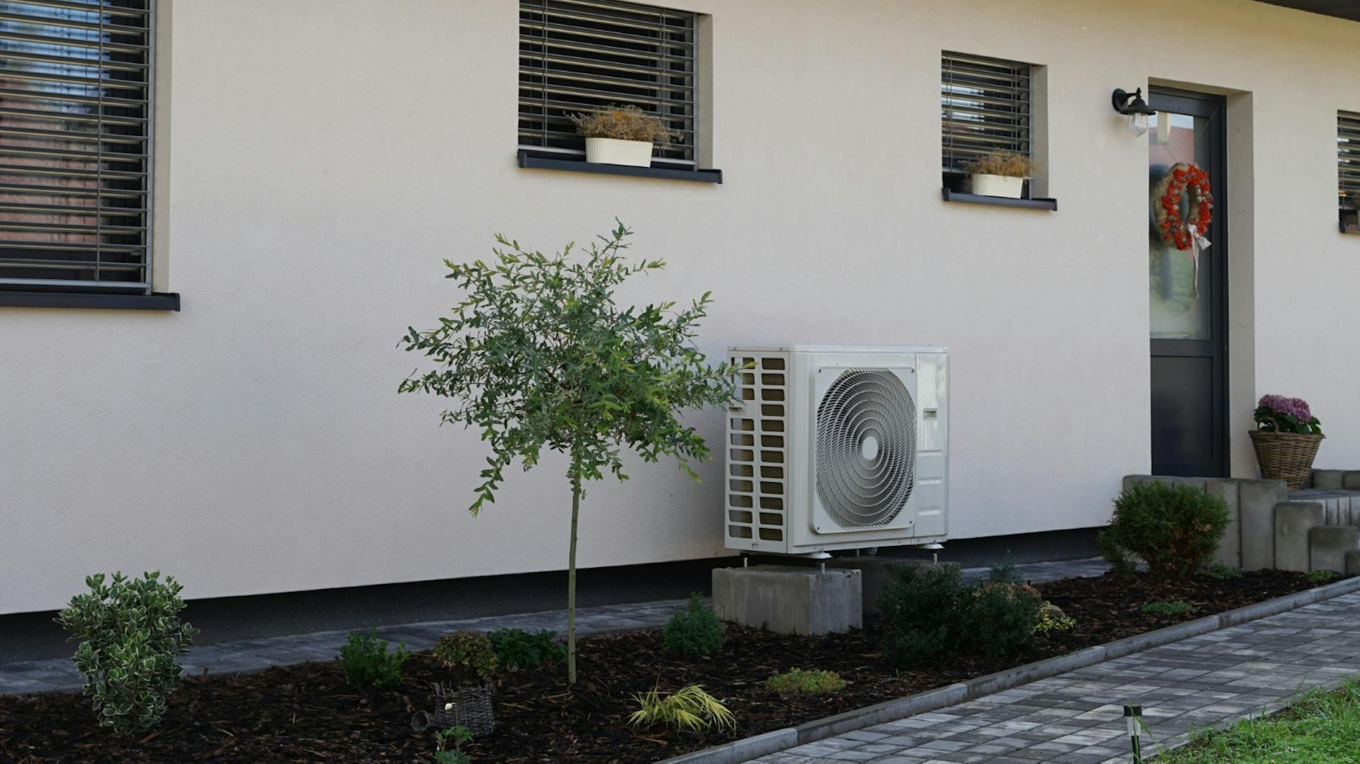 Luft-Wärme-Pumpe vor einem Wohnhaus