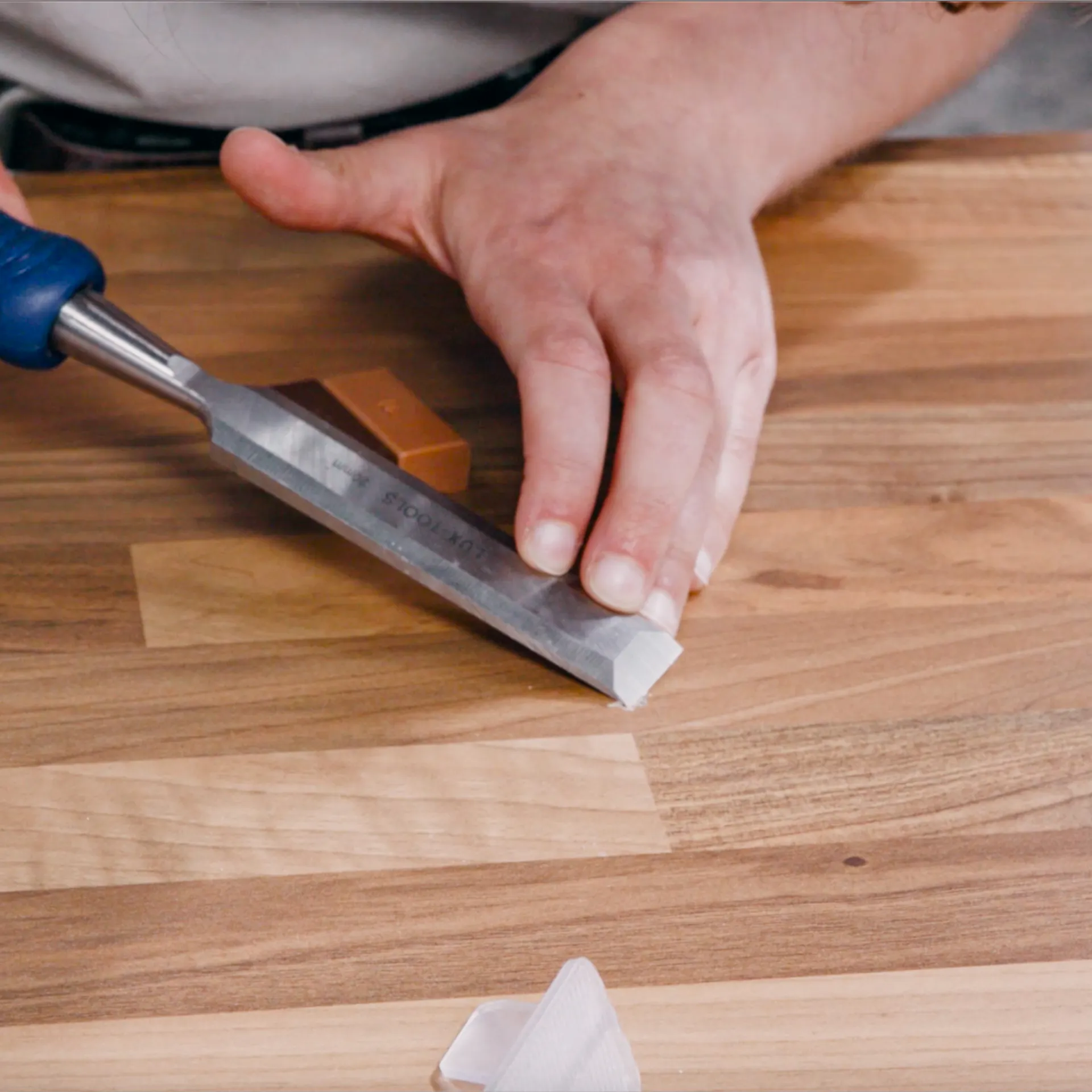 Handwerker entgratet die beschädigte Stelle mit einem Stechbeil.