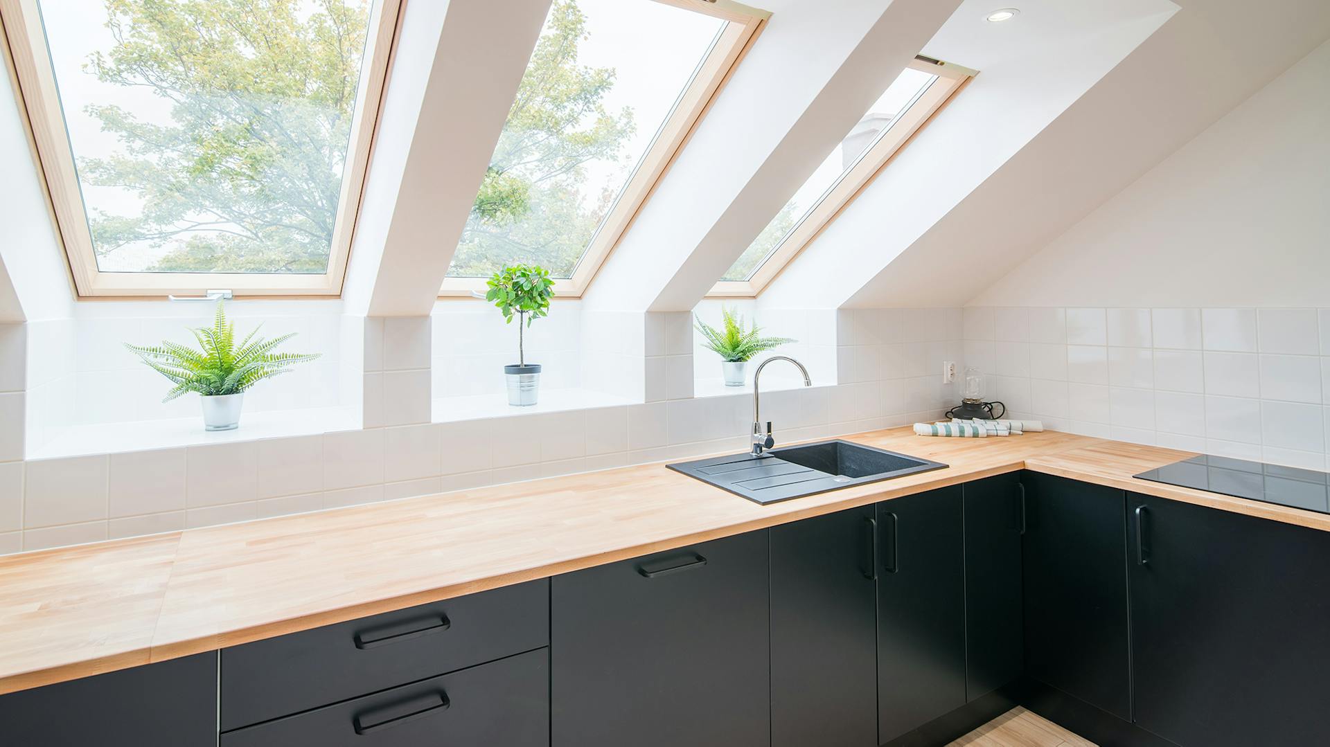 Dunkle Küche mit heller Arbeitsplatte unter Dachschräge mit Dachfenstern