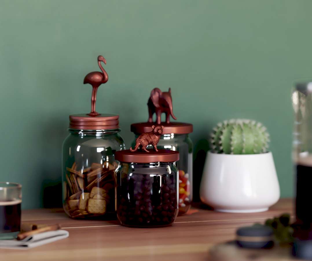 Drei Gläser, in denen sich Süßigkeiten befinden, stehen vor einer grünen Wand neben einem Kaktus. Auf die Gläserdeckel wurden Tierfiguren geklebt mit Kupferfarbe besprüht.