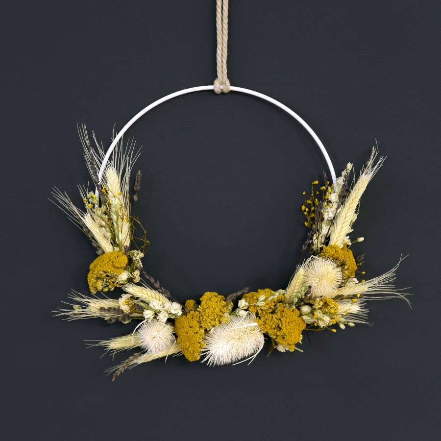 Ein Metallring mit Trockenblumen vor einer dunklen Wand