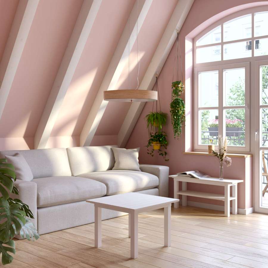 Ein heller, rosagestrichenener Raum mit einer leichten Dachschräge und großen Fenstern, in dem helle Möbel und einige Pflanzen sind