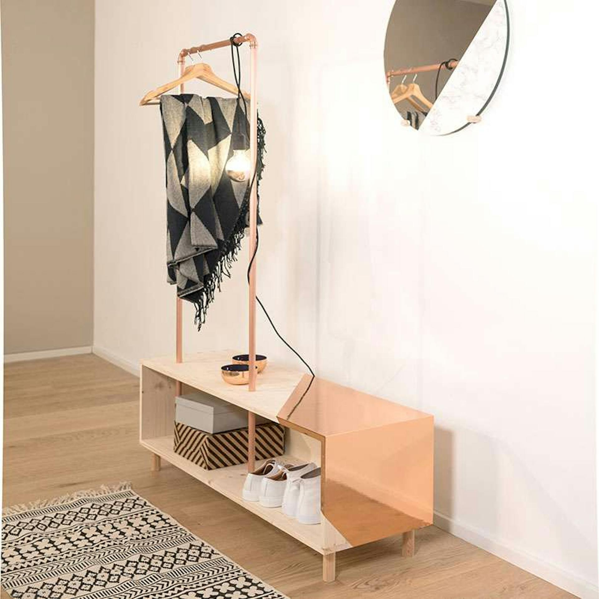 Eine Garderobe, die vor einer hellen Wand steht, wurde mit kupferfarbener Folie gestaltet.