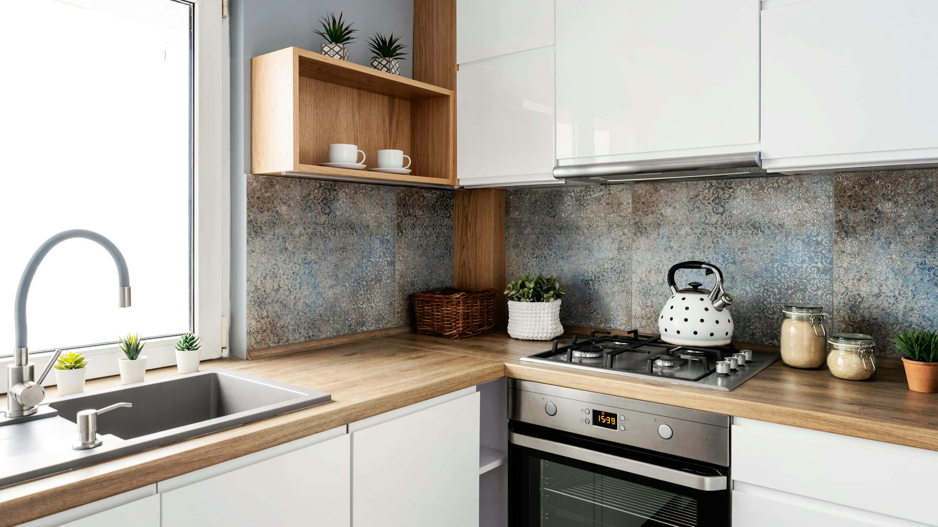 Moderne weiße Küche mit Dekorrückwand und hölzerner Arbeitsplatte.