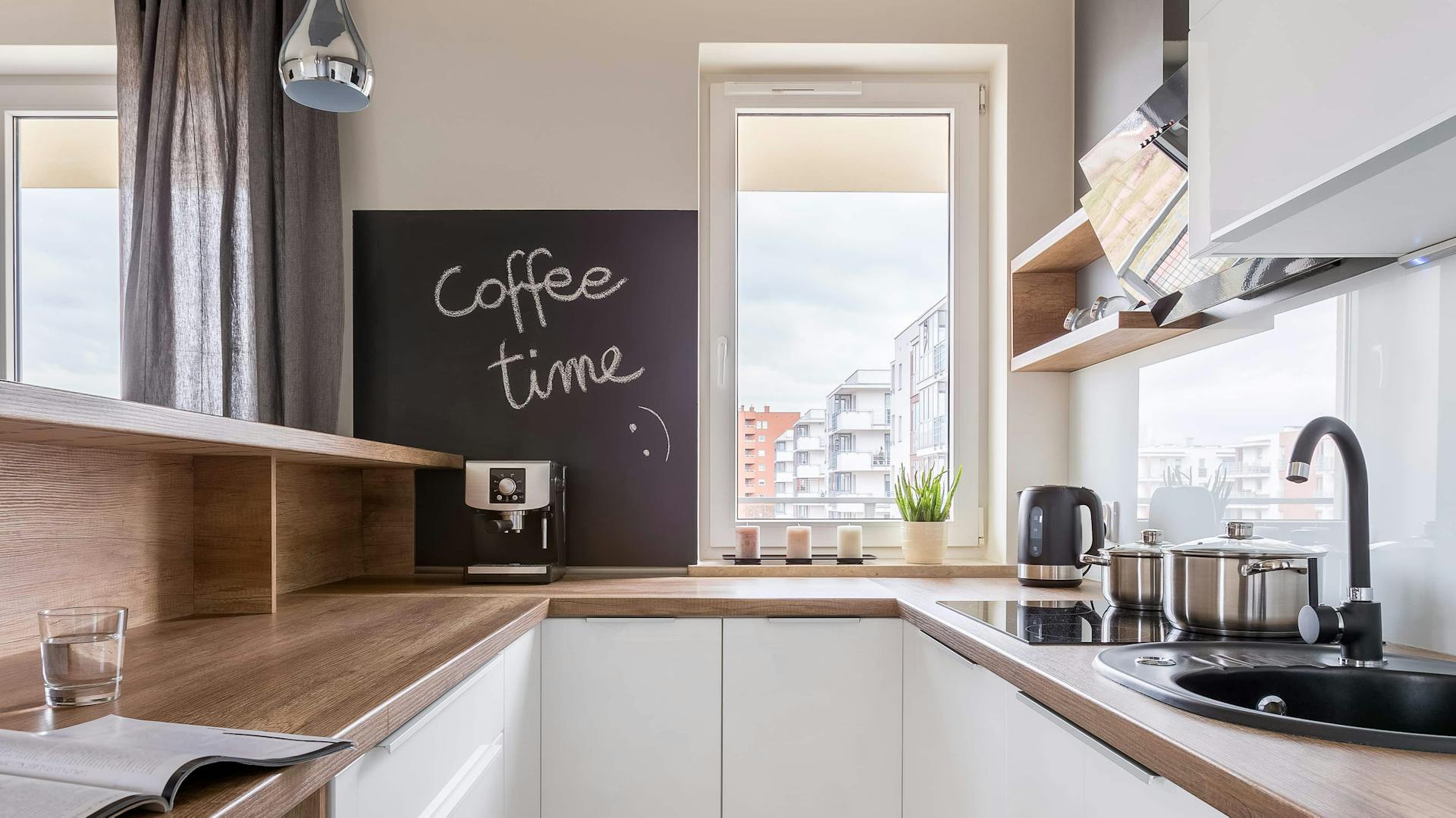 Moderne Küche mit weißen Fronten und einer Arbeitsplatte in Holzoptik.