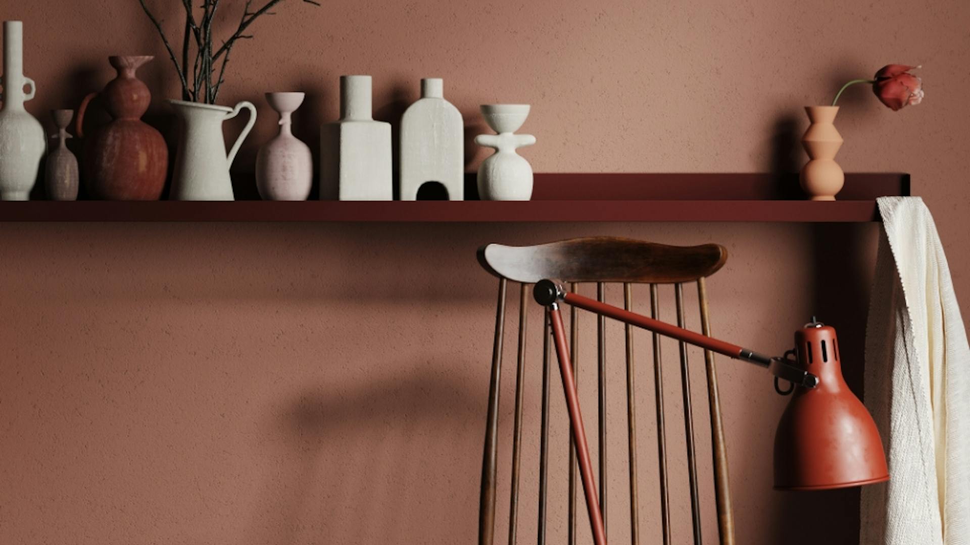Parete marrone con sedia e mensola decorata con vasi bianchi.