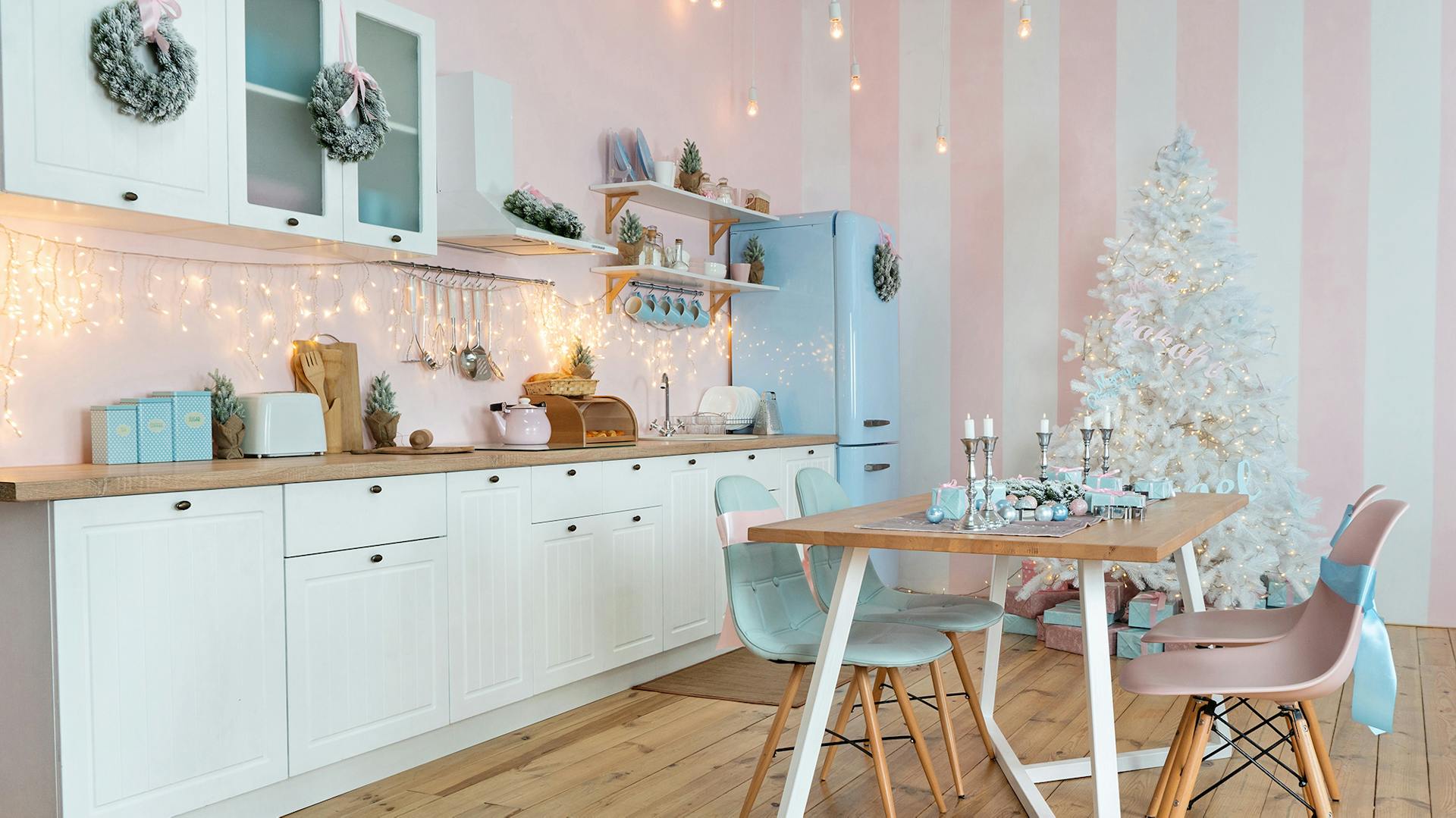 Romantische weiße Küche mit rosa-gestreifter Tapete und Lichterkette